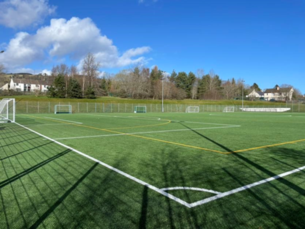 A spacious area of artificial turf featuring pitch markings and multiple goal nets positioned along each side.