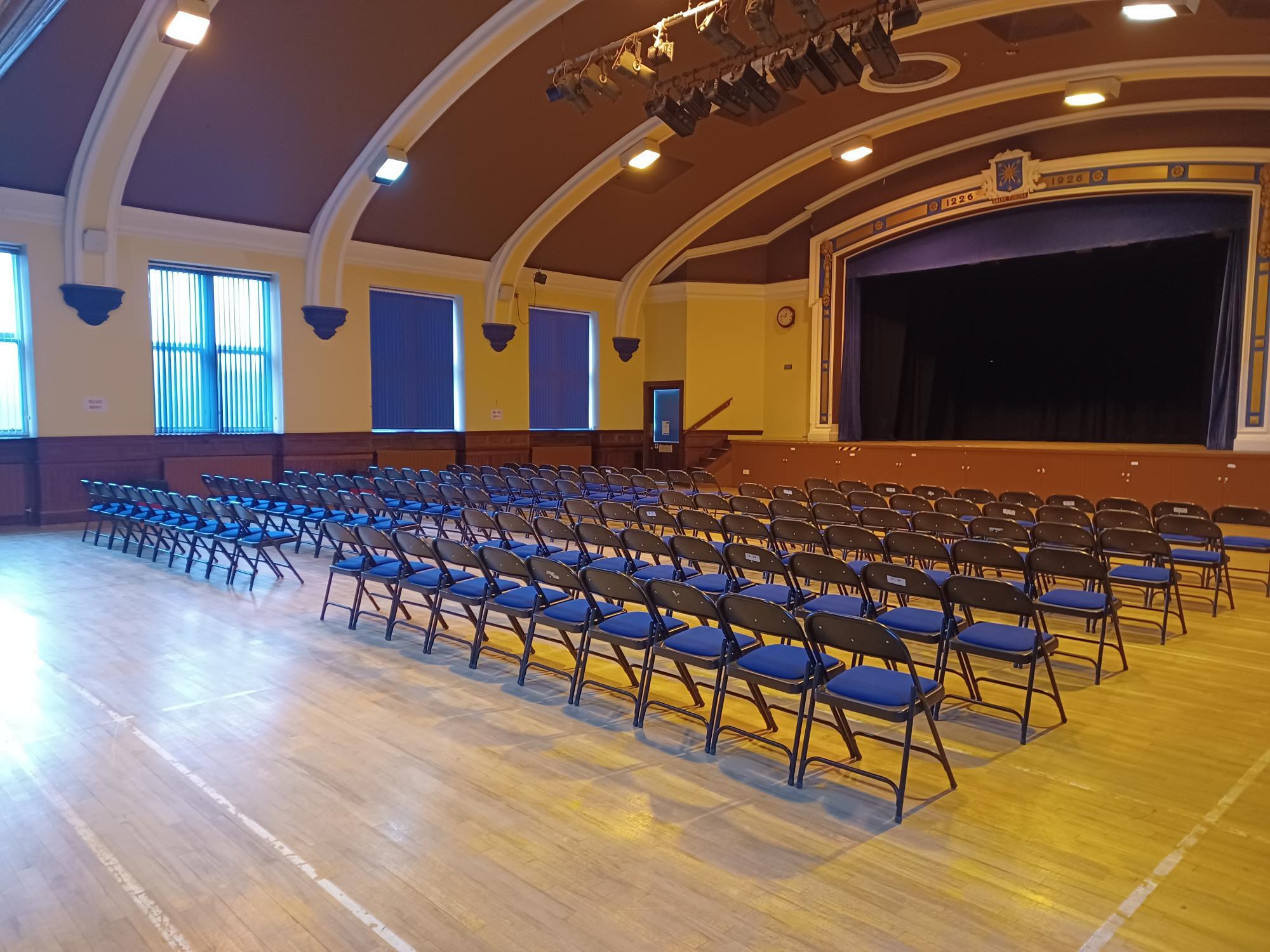 The hall features seating arranged to face the main stage.