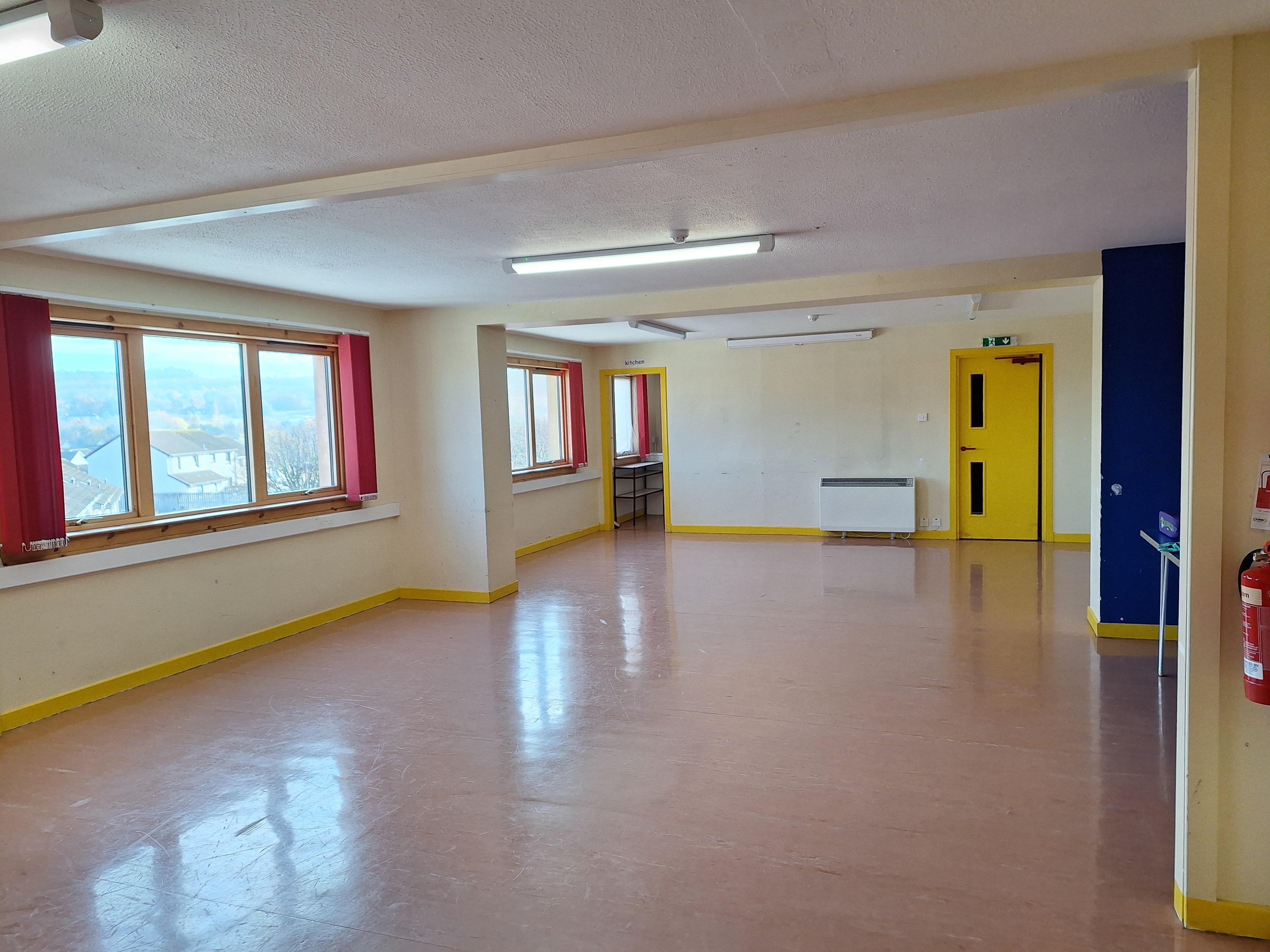 A spacious room featuring linoleum flooring and abundant natural light streaming in through windows located along the side wall.