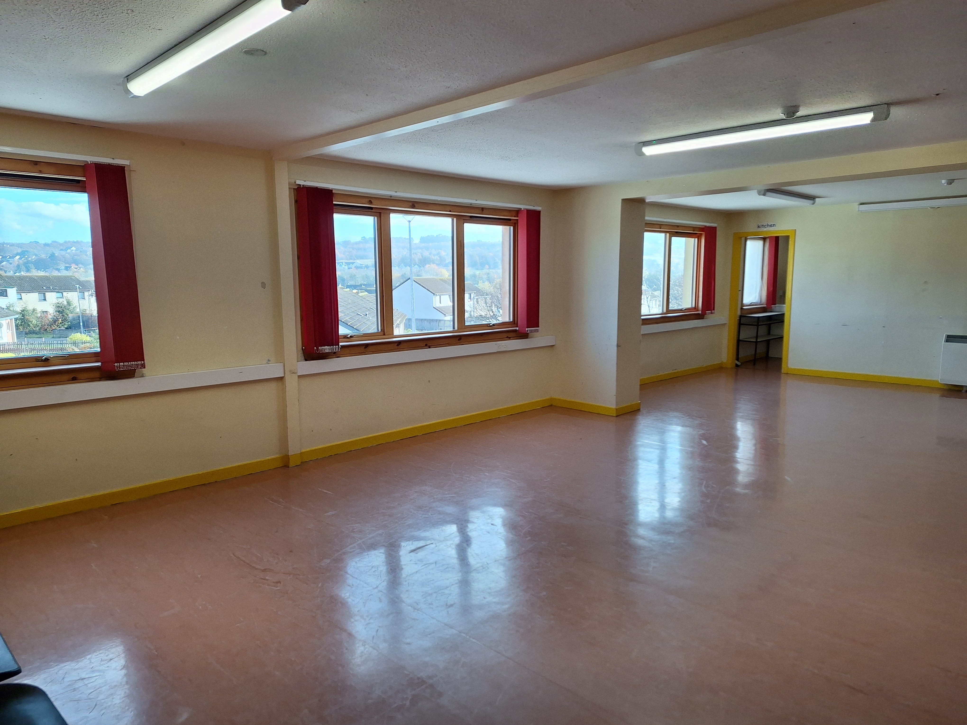 A spacious room featuring linoleum flooring and abundant natural light streaming in through windows located along the side wall.