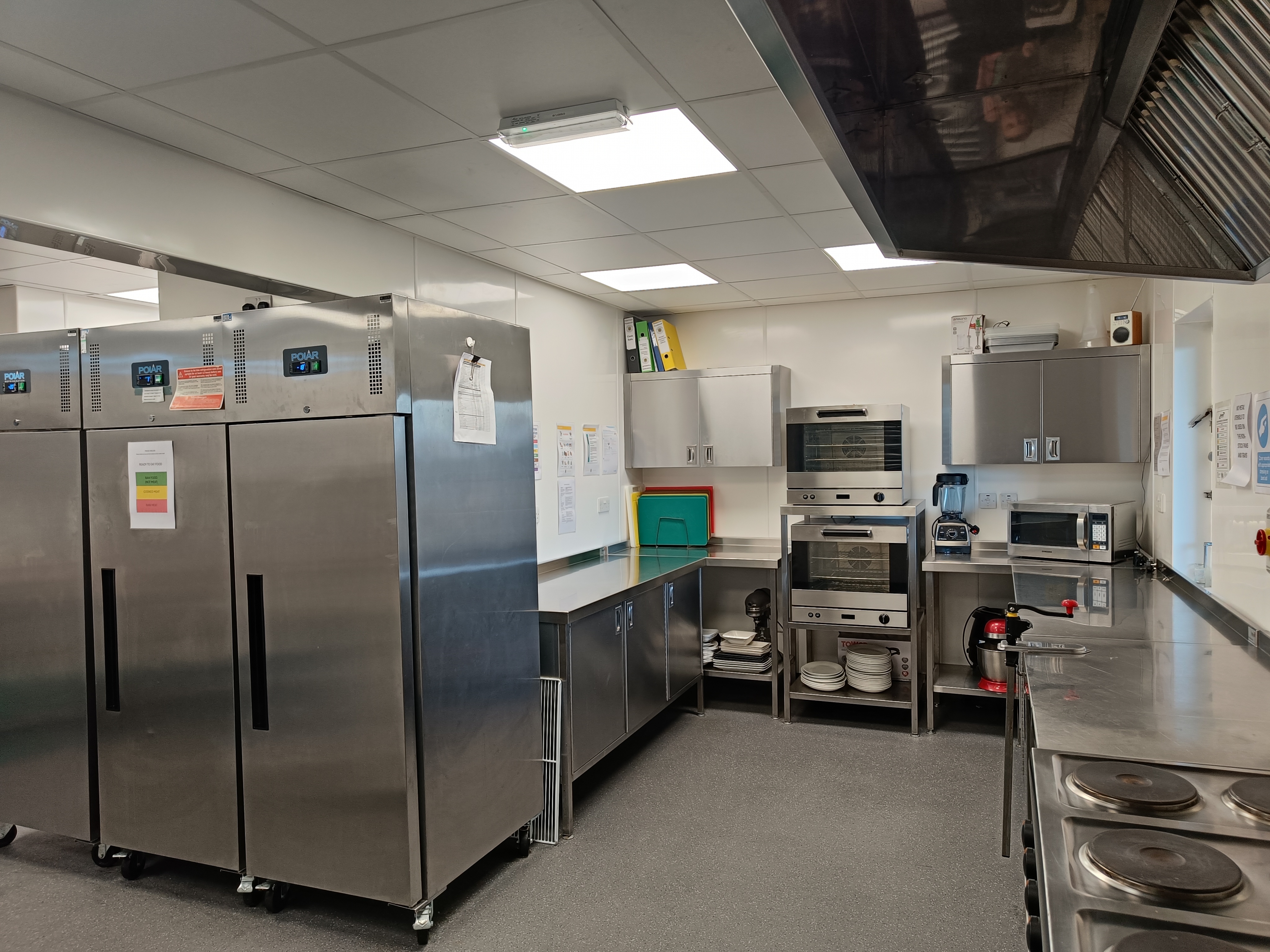Catering kitchen with industrial-sized oven, hob and microwave oven.