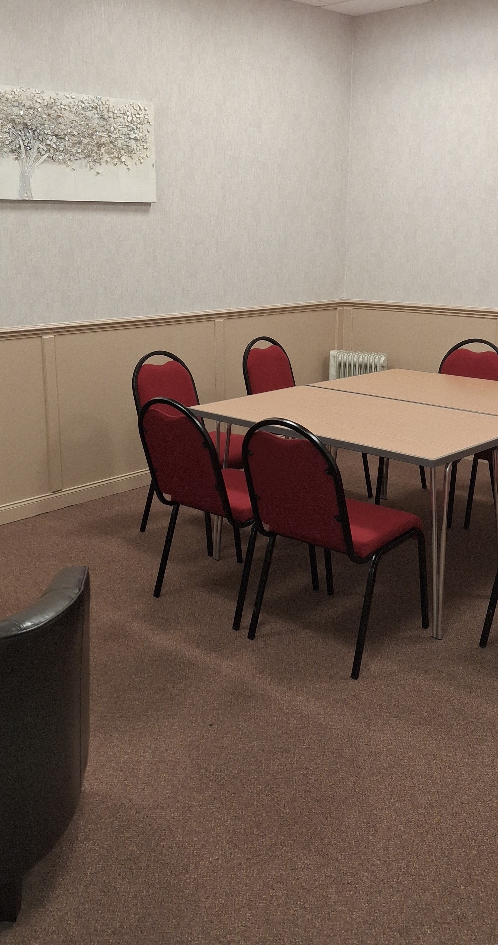 A compact, carpeted room featuring a meeting table encircled by chairs.