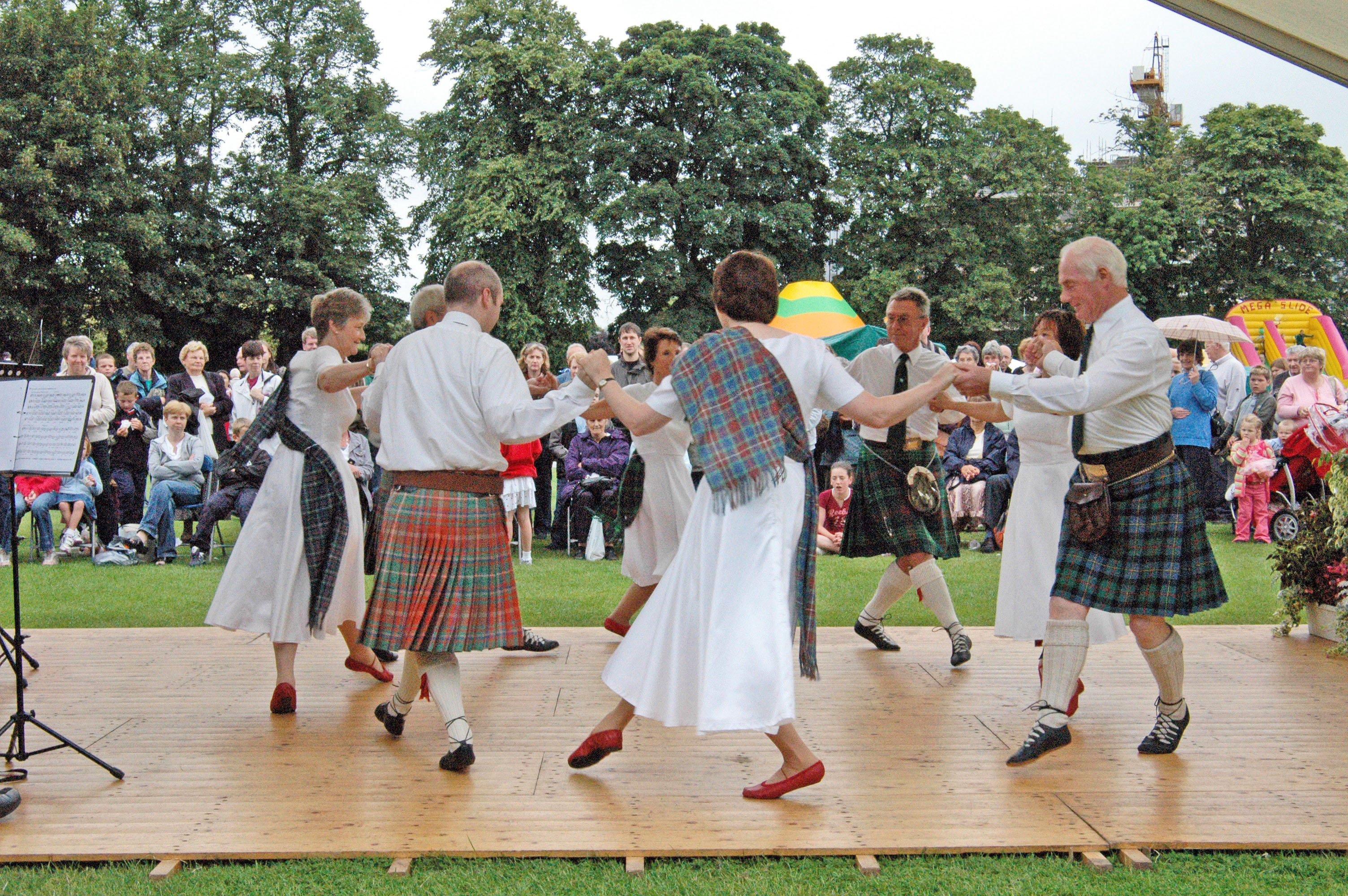 Colour photograph of couples Scottish country dancing on an outdoor stage at the Marymas Fair, 2006, with a crowd of spectators watching.