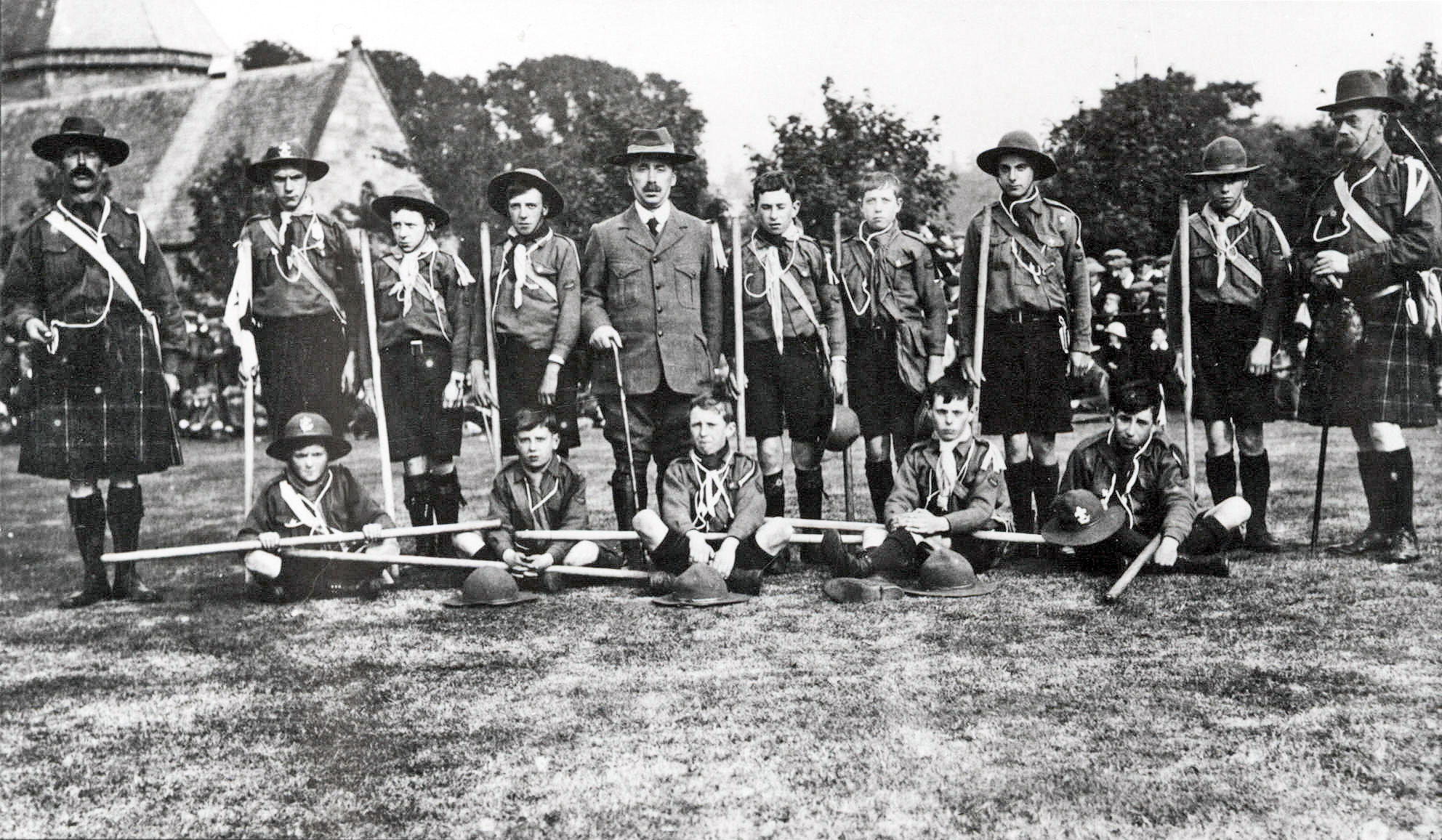 Black and white group photograph of the Gairloch Troop of Boy Scouts, taken at the Northern Meeting Park, Inverness, on 19 September 1913. Scout leaders in kilts flank rows of uniformed boys holding staffs.