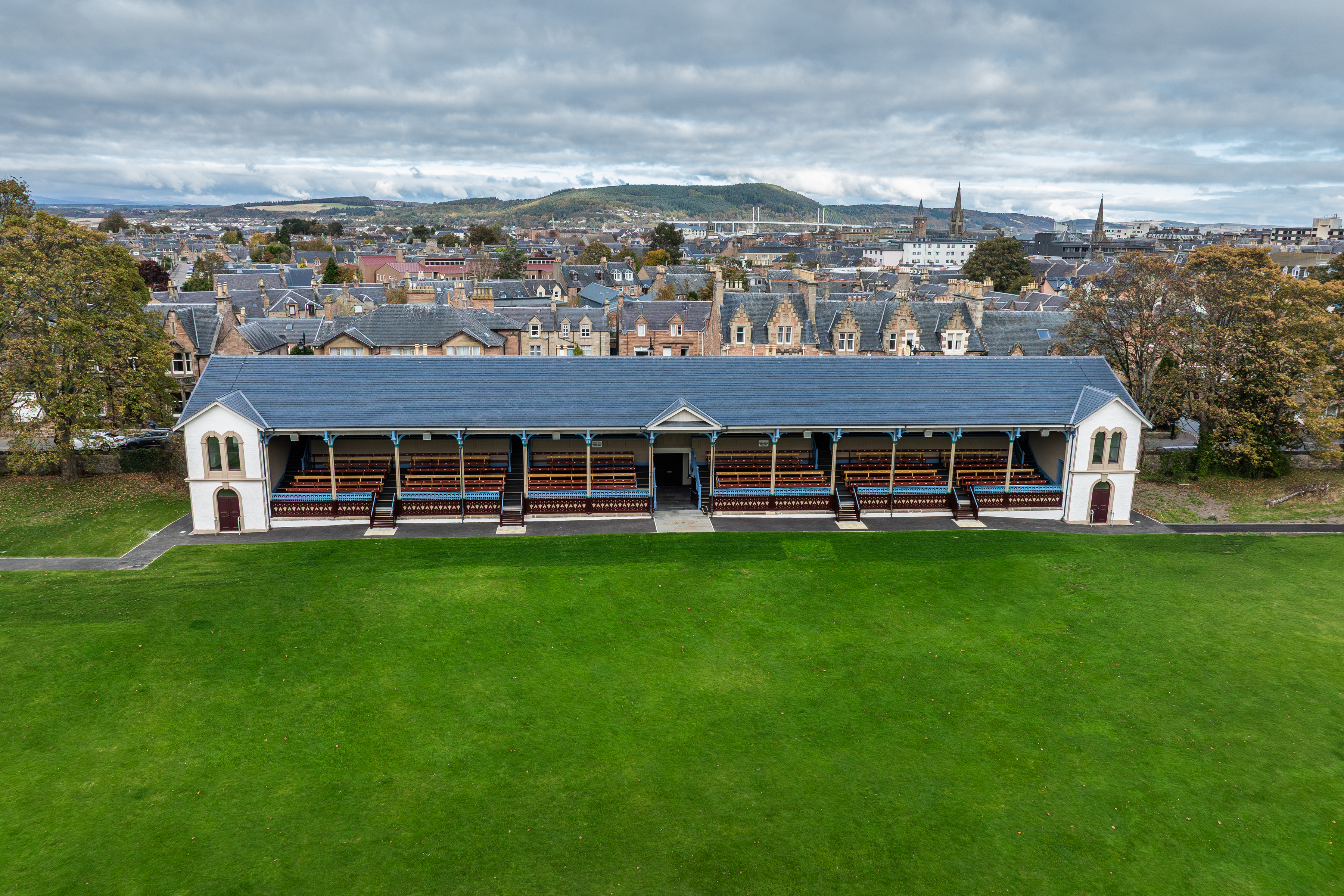 The picturesque Victoria Grandstand is complemented by a spacious green lawn in the foreground, with the city of Inverness serving as a stunning backdrop.