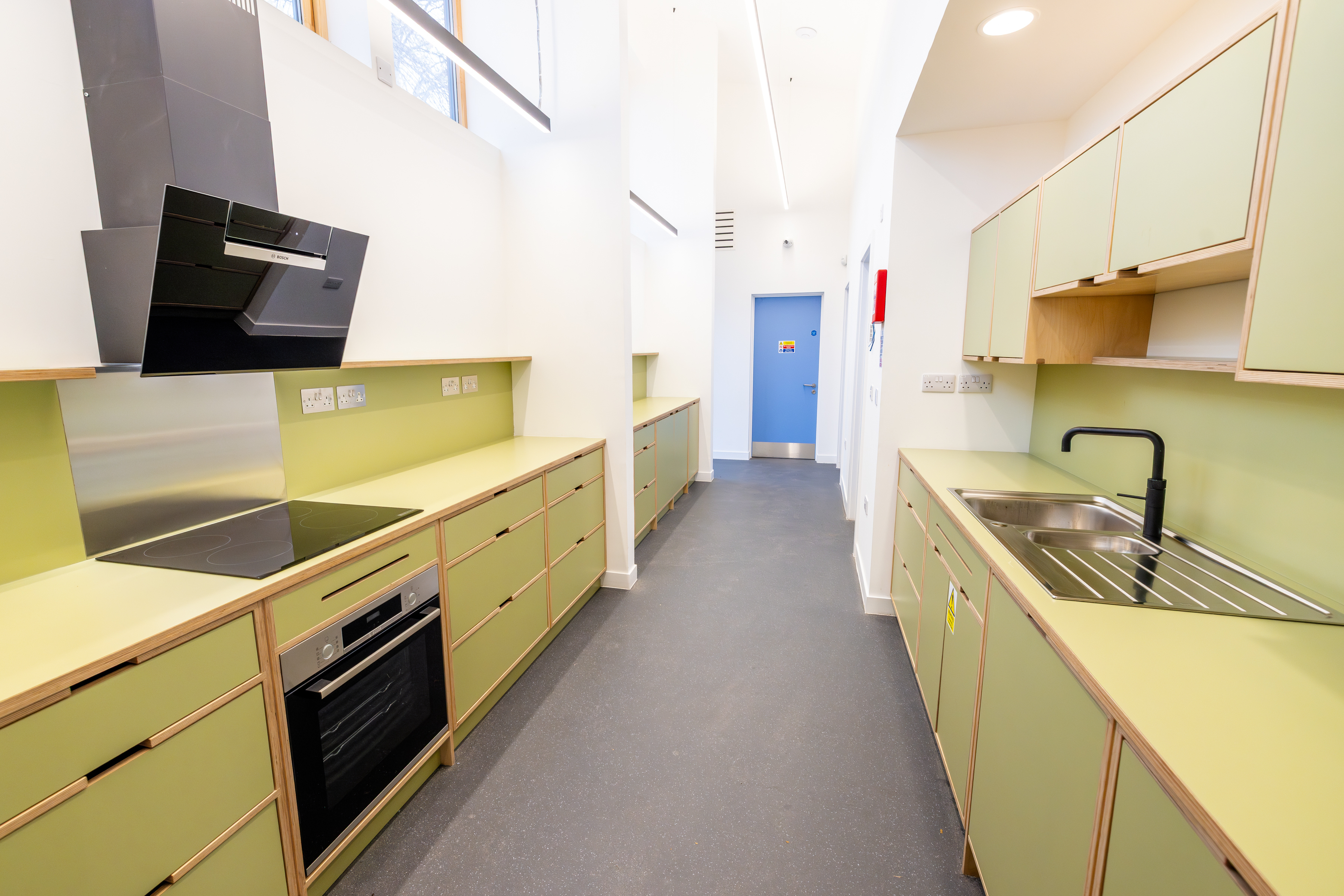 A compact kitchen featuring a cooker, hob, extractor fan, and sink.