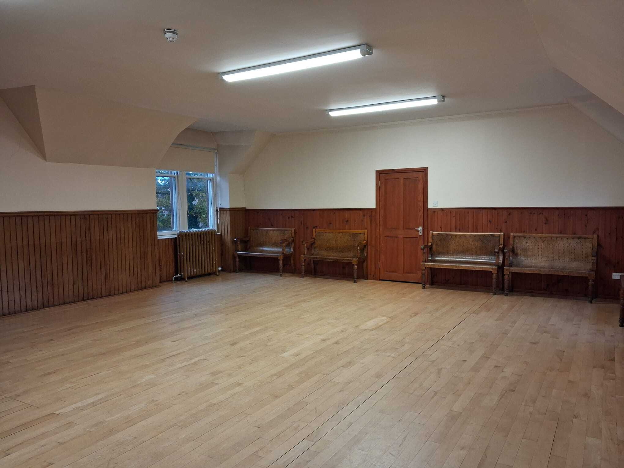 The Ceilidh room is an expansive hall featuring hardwood flooring and abundant natural light that pours in through large windows.