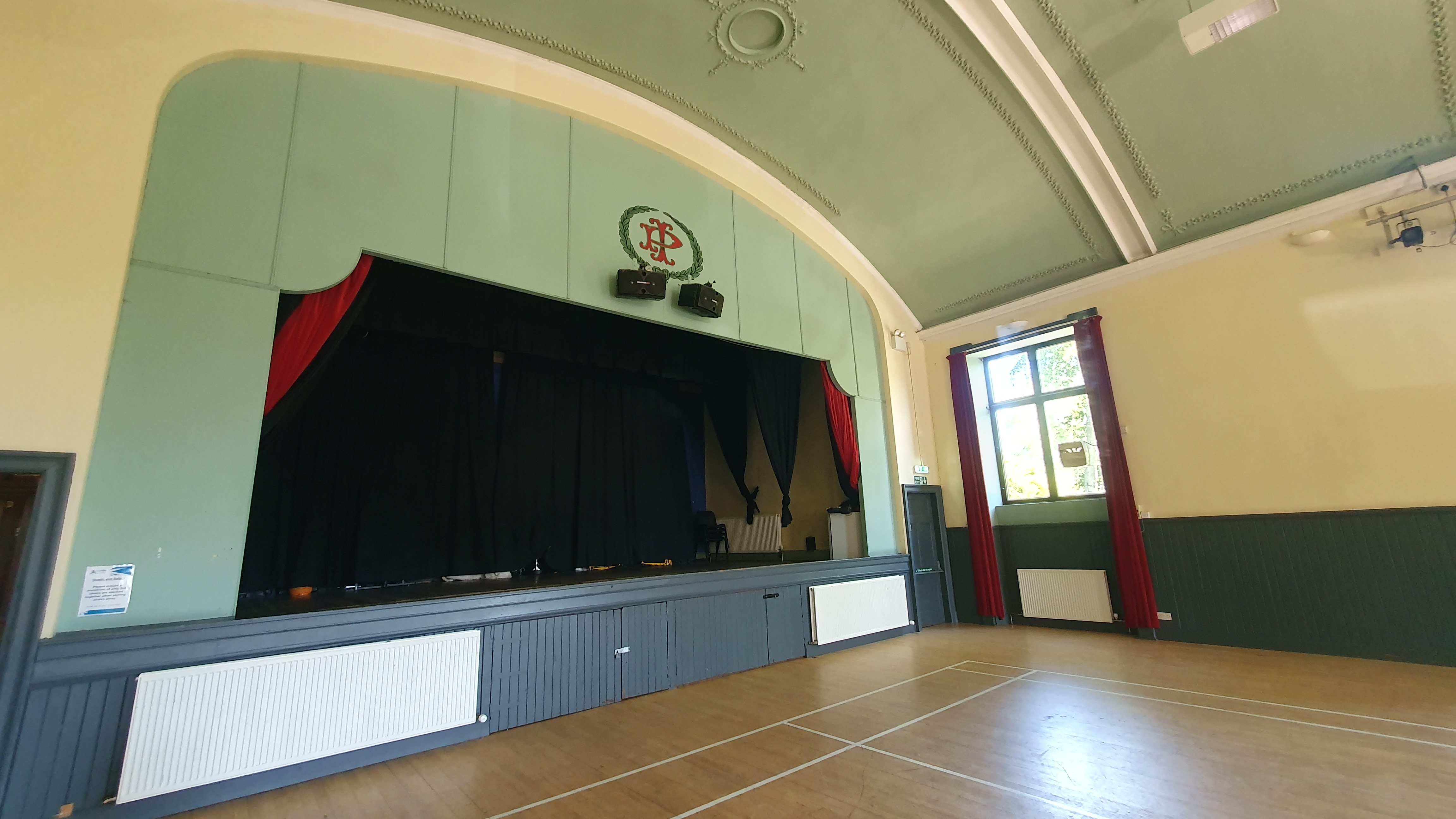 A hall featuring a stage adorned with curtains.