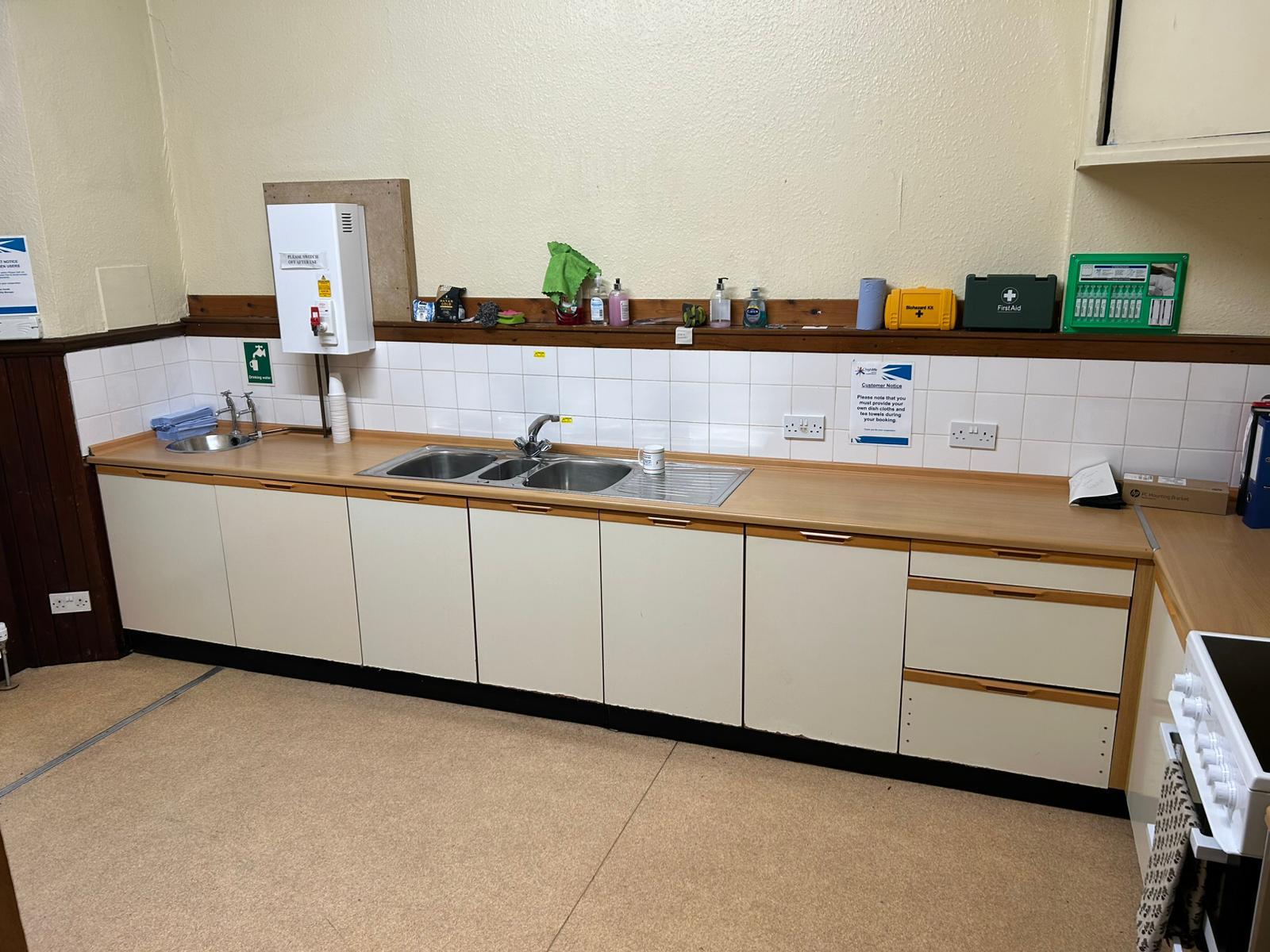A kitchen equipped with cabinets, work surfaces, sink, and oven.