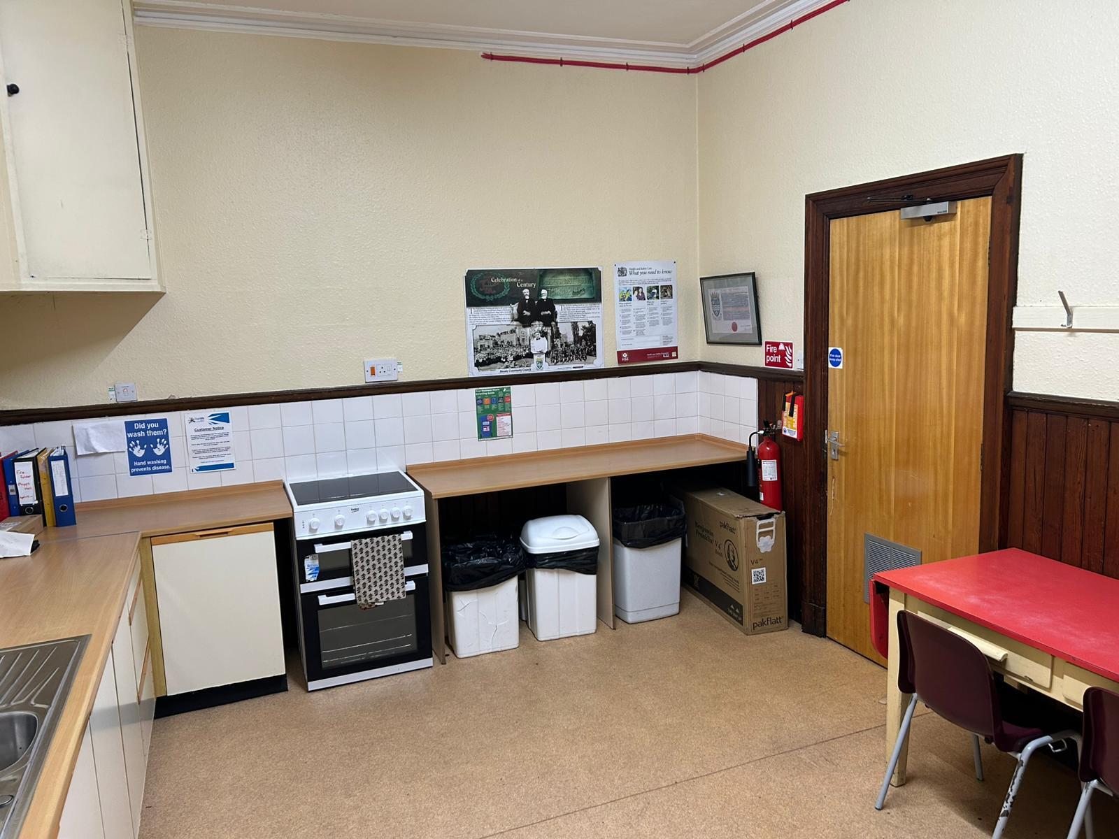 A kitchen equipped with cabinets, work surfaces, sink, oven & hobb and a side table.