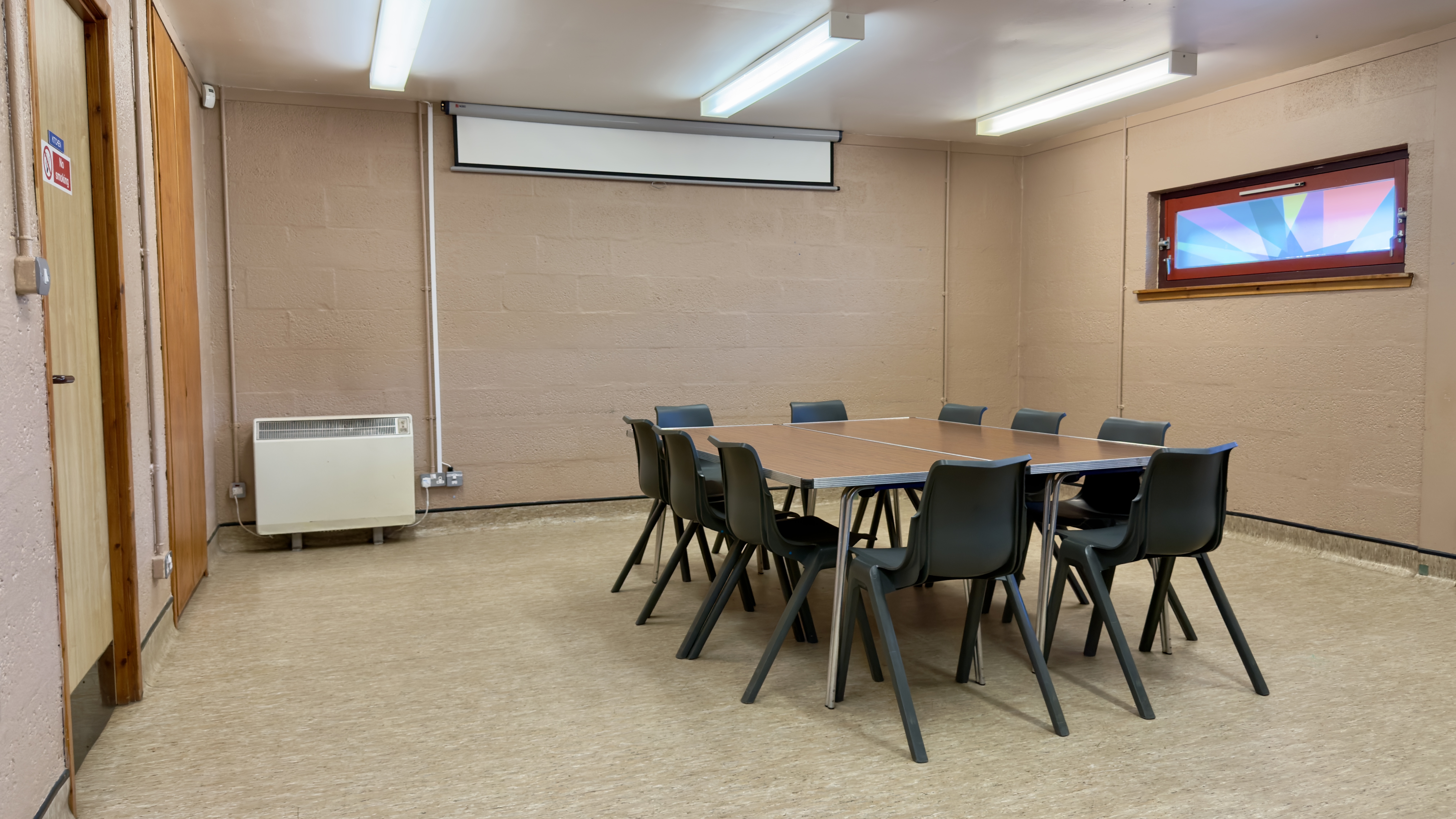 A meeting room with two large tables and chairs arranged in a square in the centre of room.
