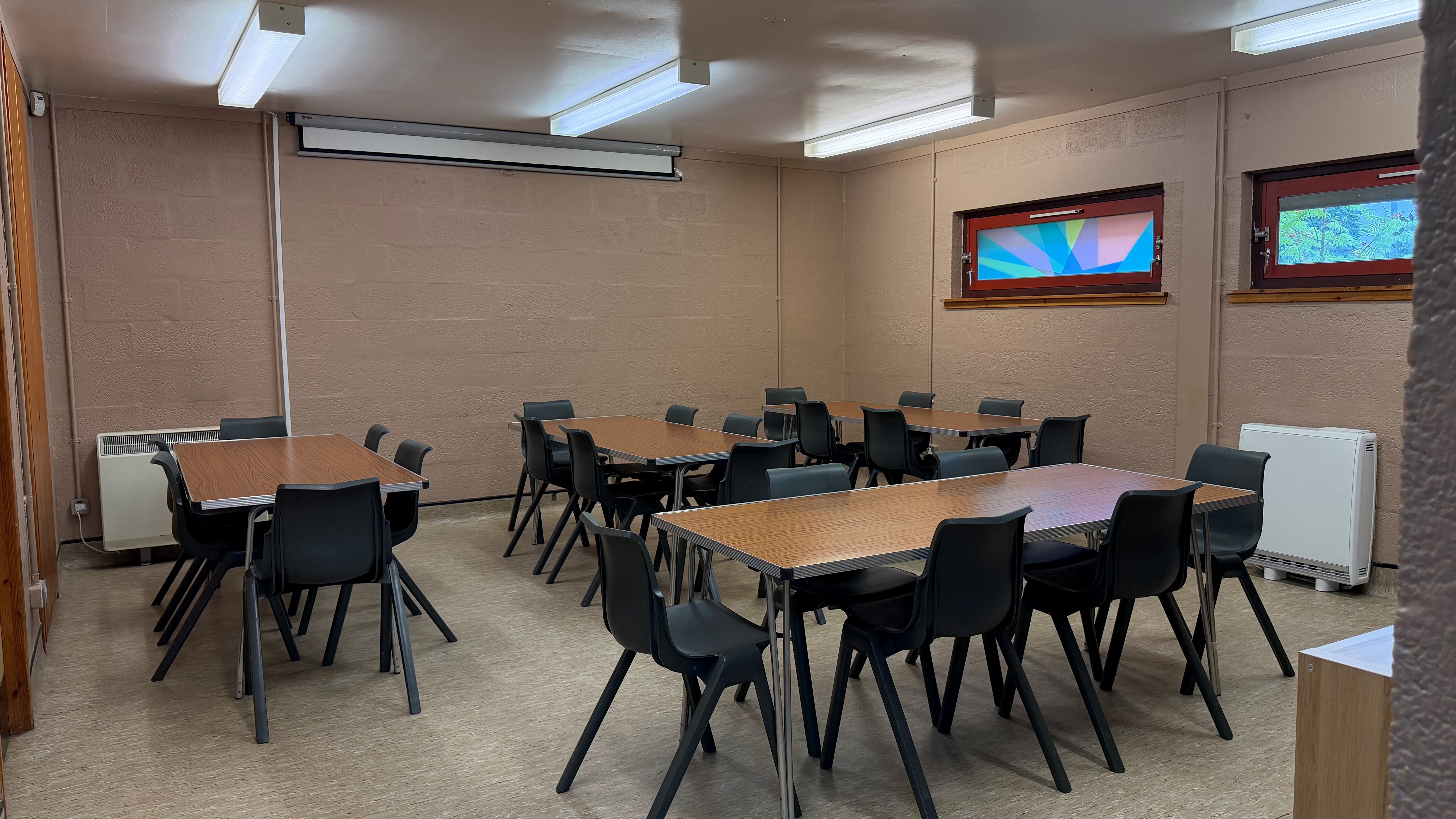 4 large tables with 6 chairs around each. Training-style setup in the room.