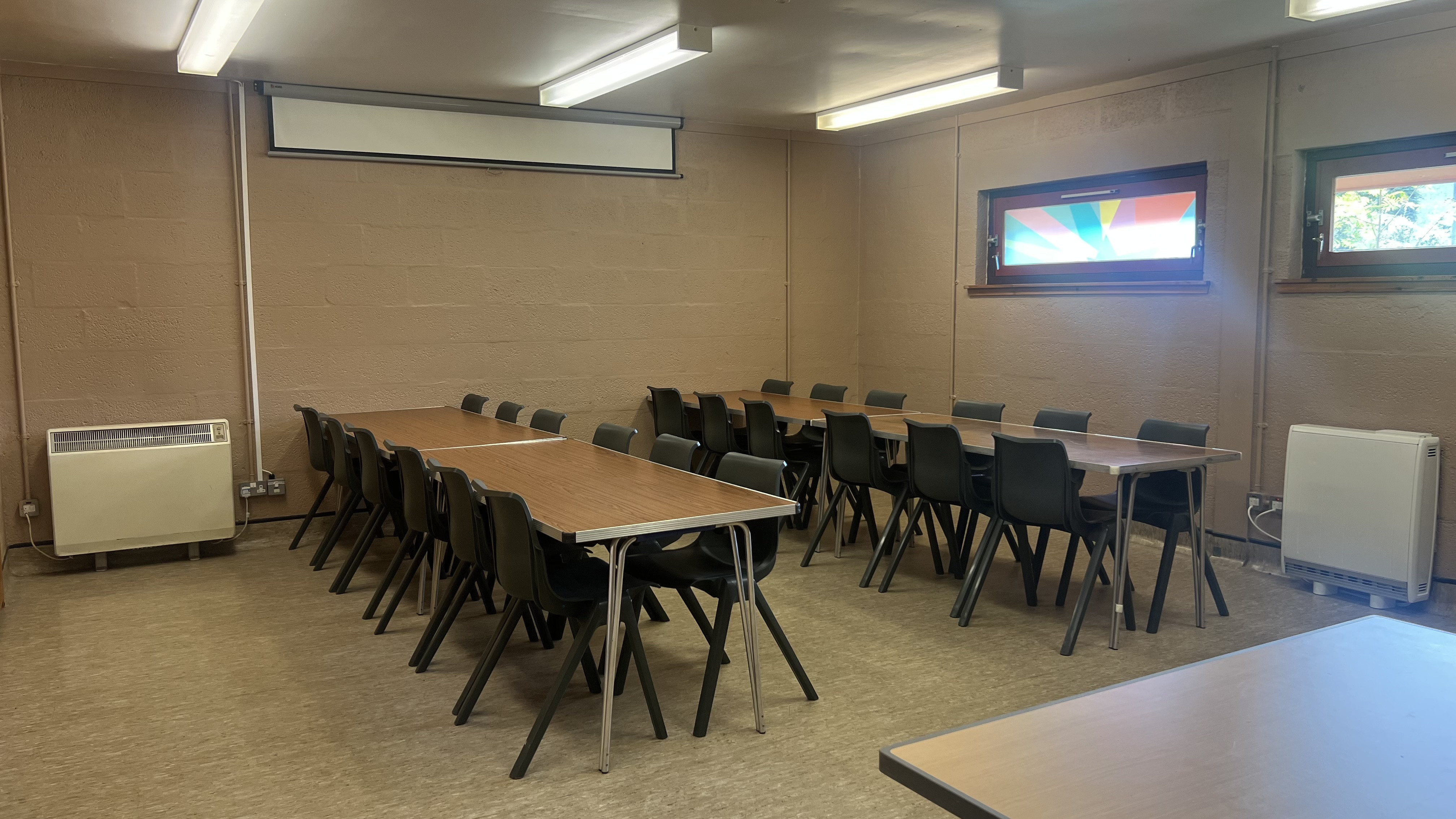 The King Duncan's room is a versatile square space that can be configured for various purposes. This photo showcases the room arranged for a party, featuring long tables and chairs positioned in the centre.