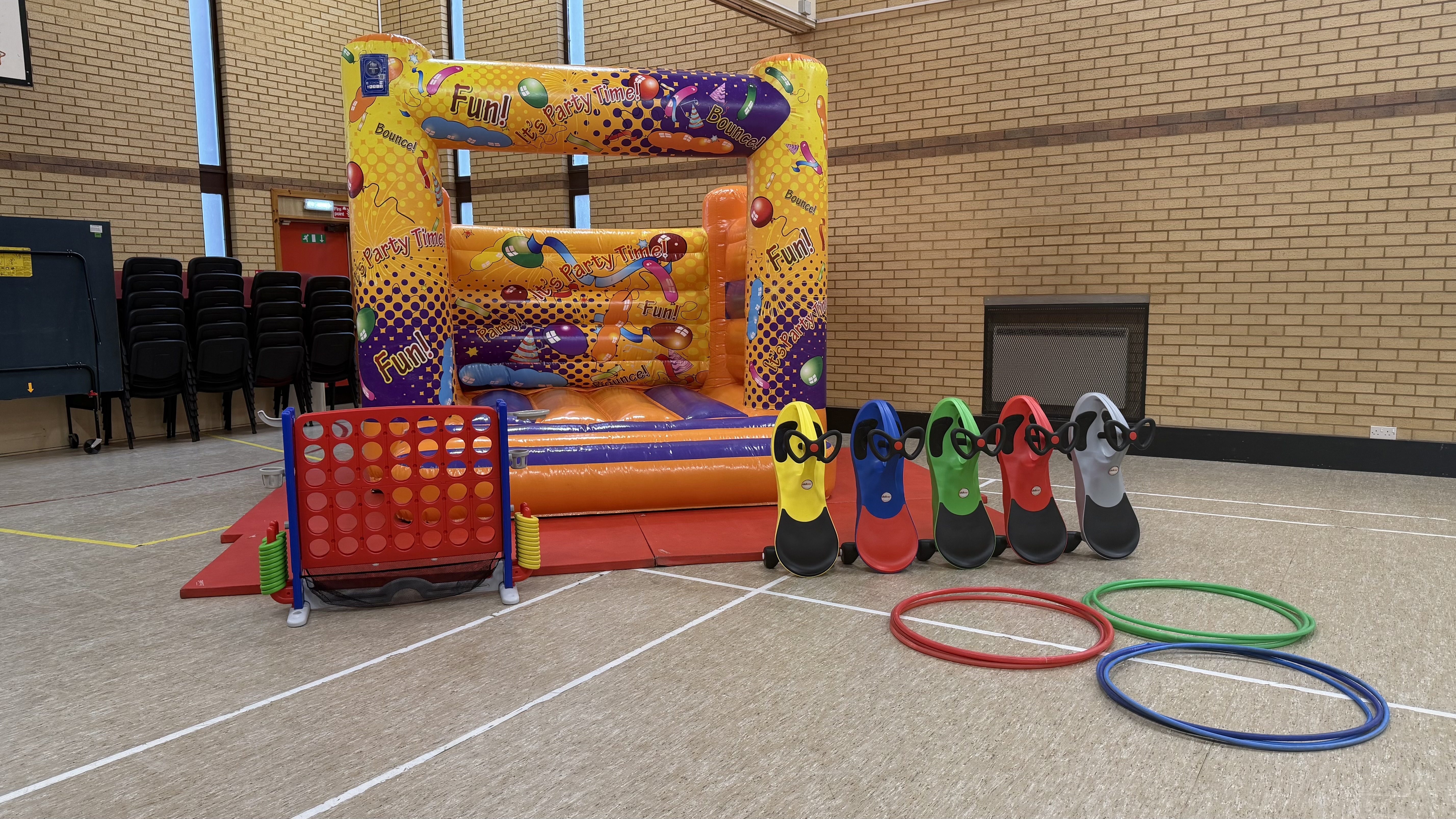 Small bouncy castle with yellow and purple print. Giant Connect 4 game, five ride-on cars and hula hoops.