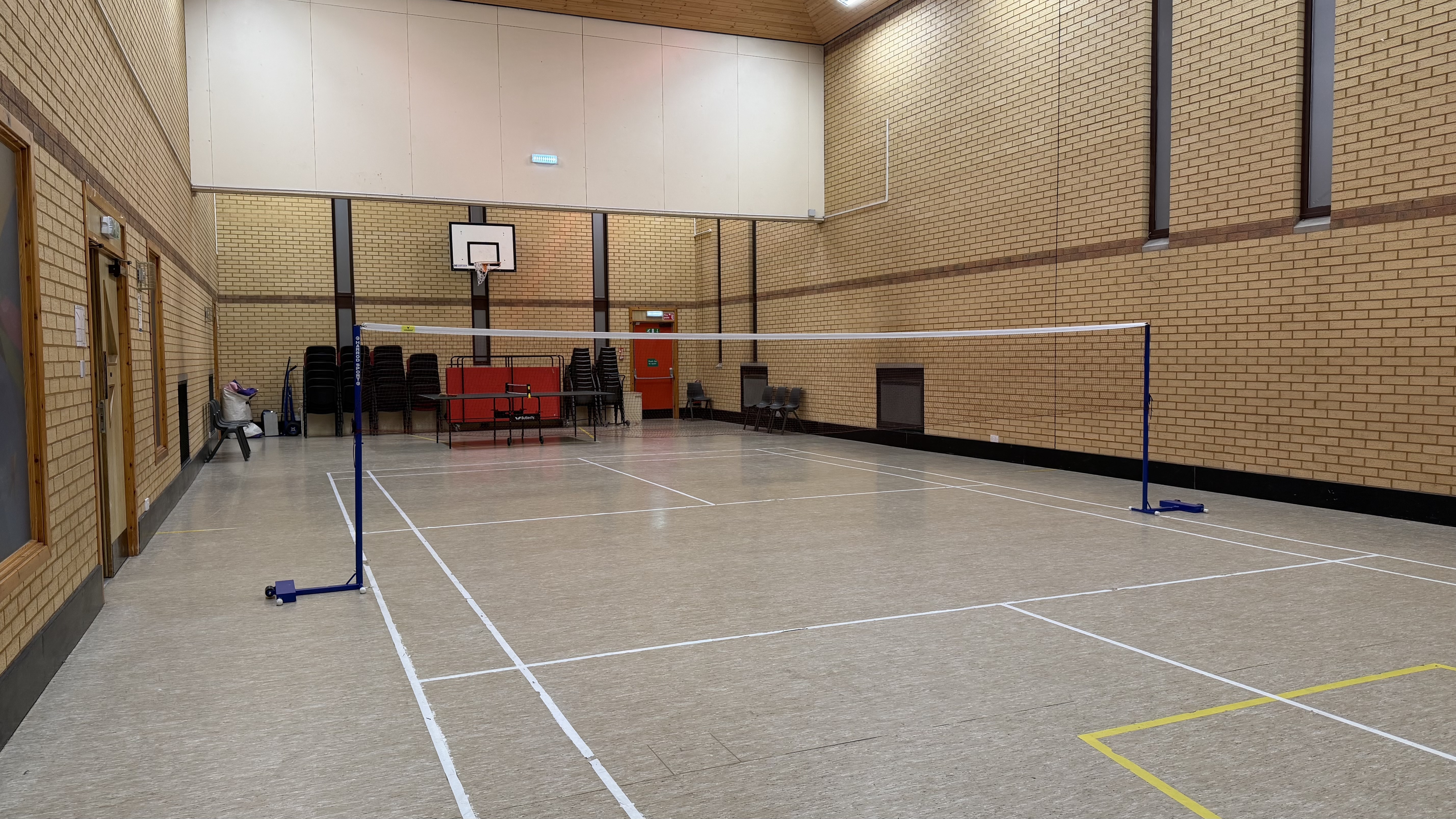 A badminton court set up in a sports hall with a net across the centre.