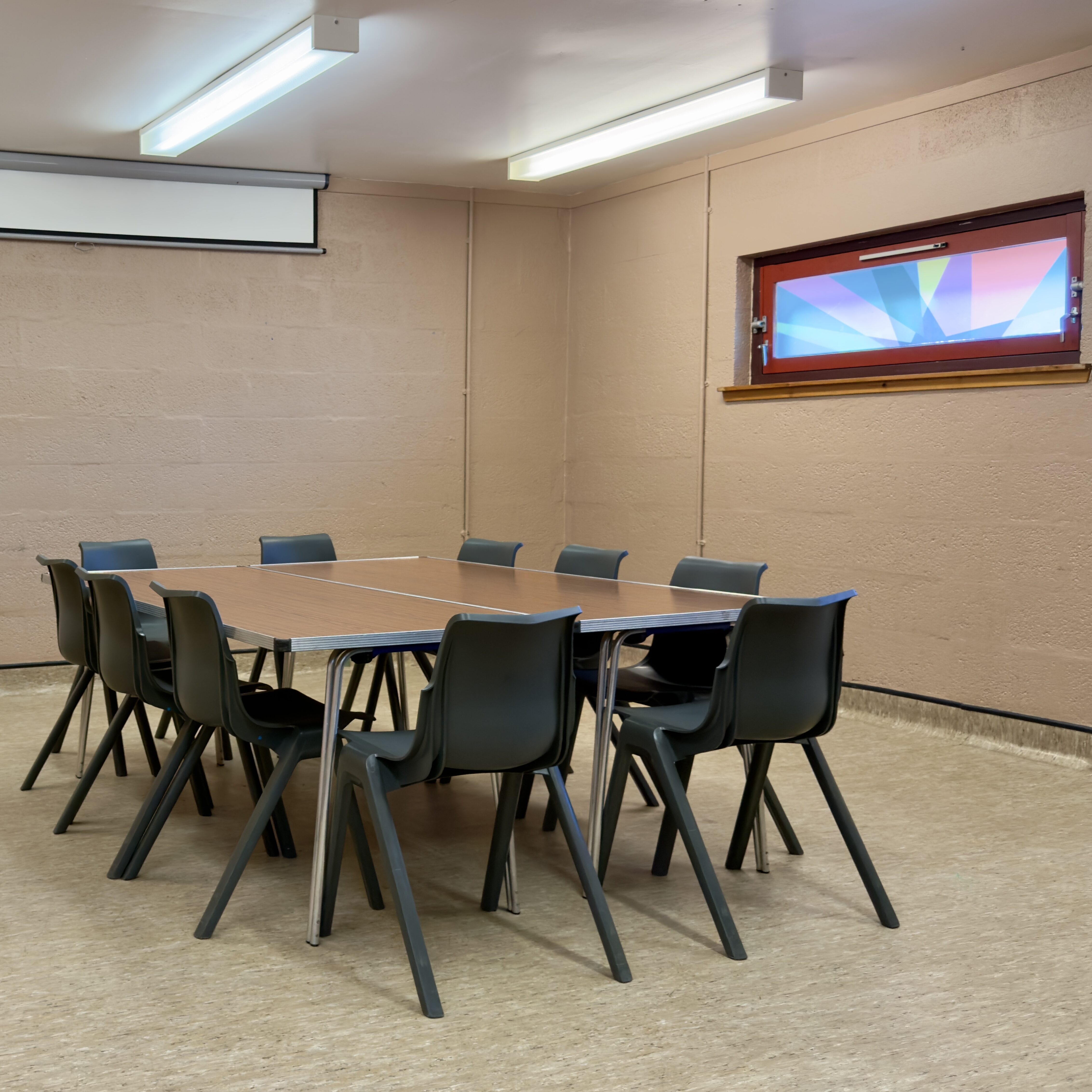 A meeting room with a large table and chairs arranged in a square in the centre.