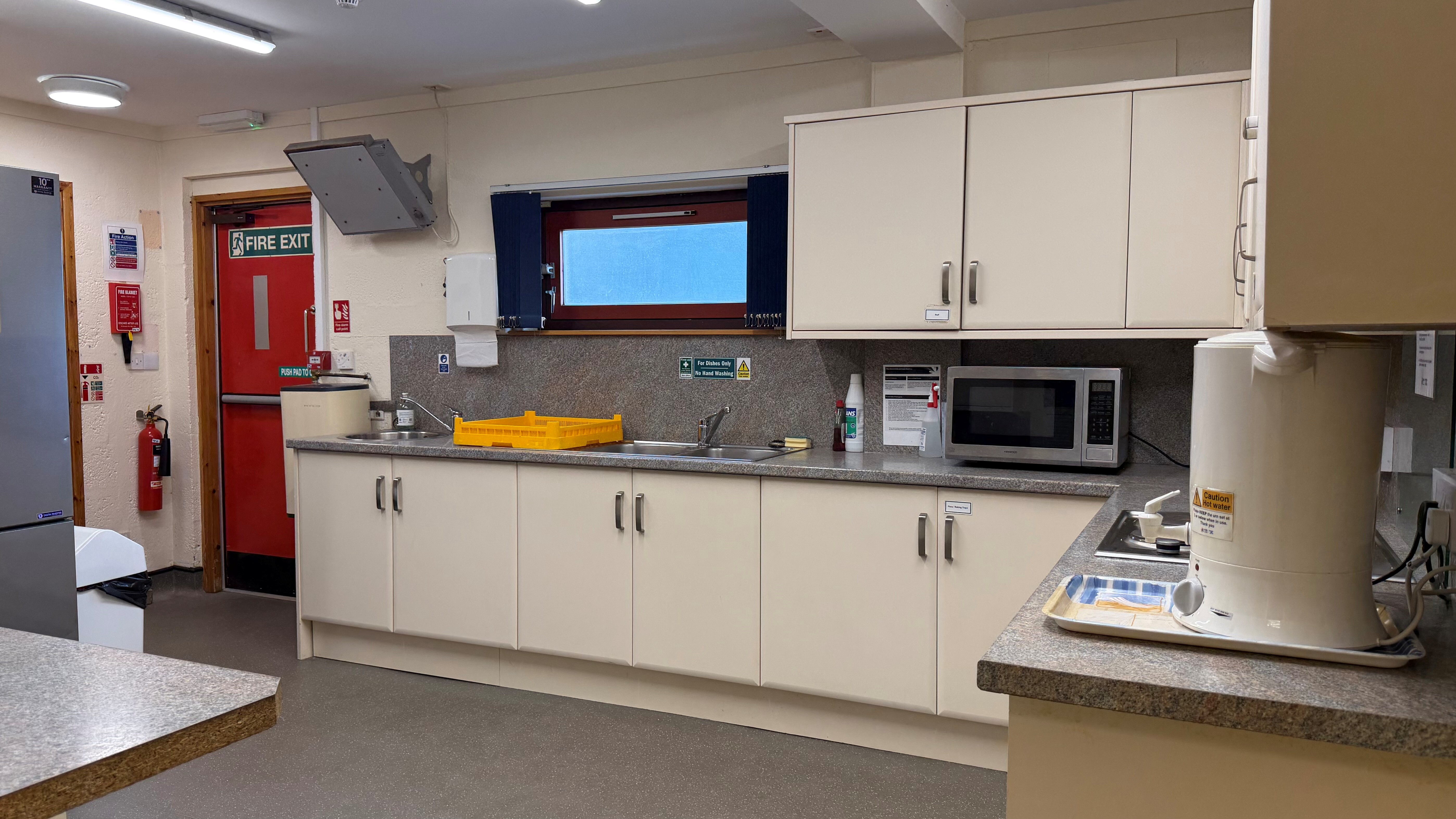 Kitchen at Raigmore Community Centre with cream cabinets, double sink, microwave, and hot water urn.