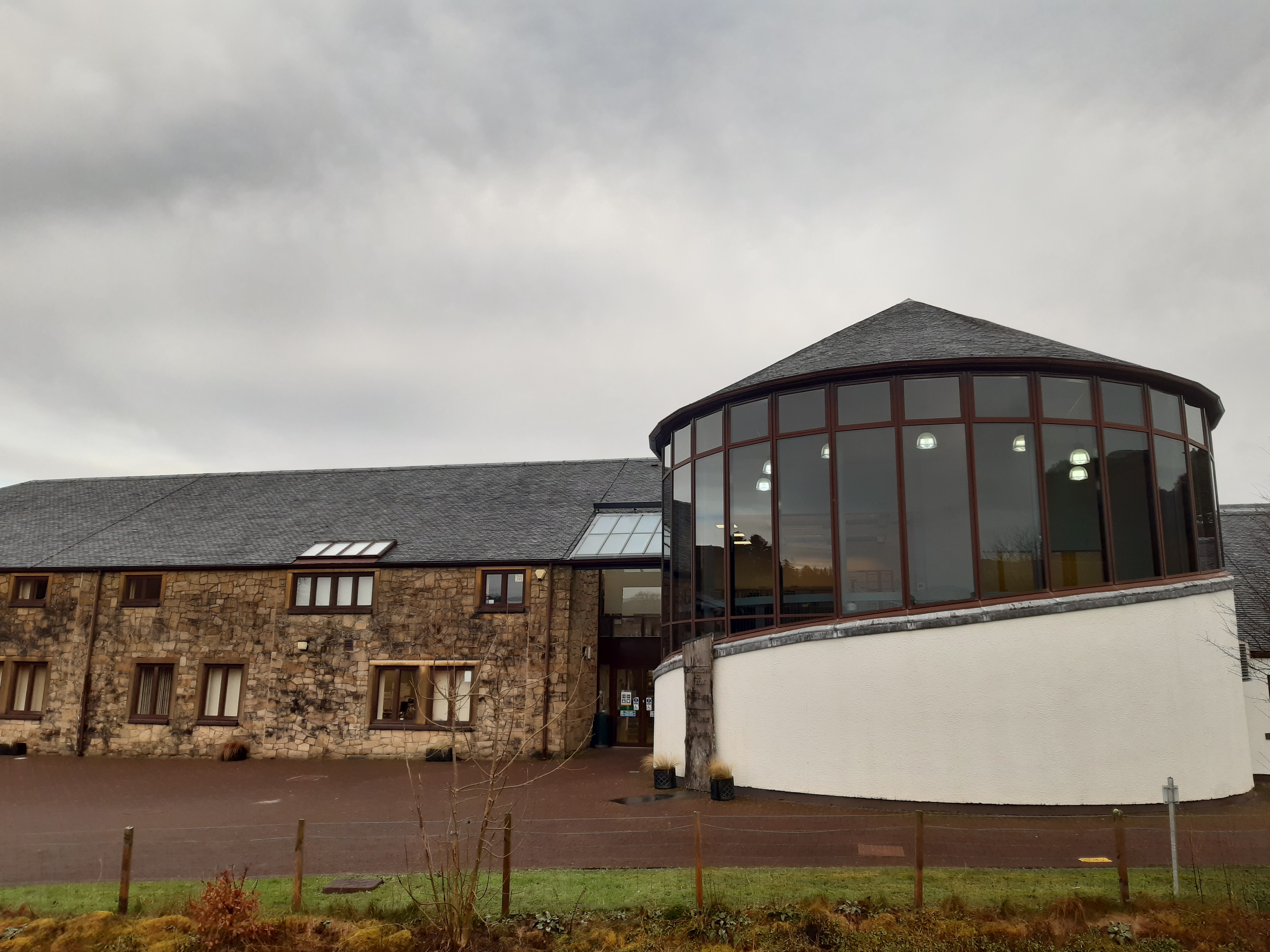 A contemporary building featuring an oval room with floor to ceiling windows.