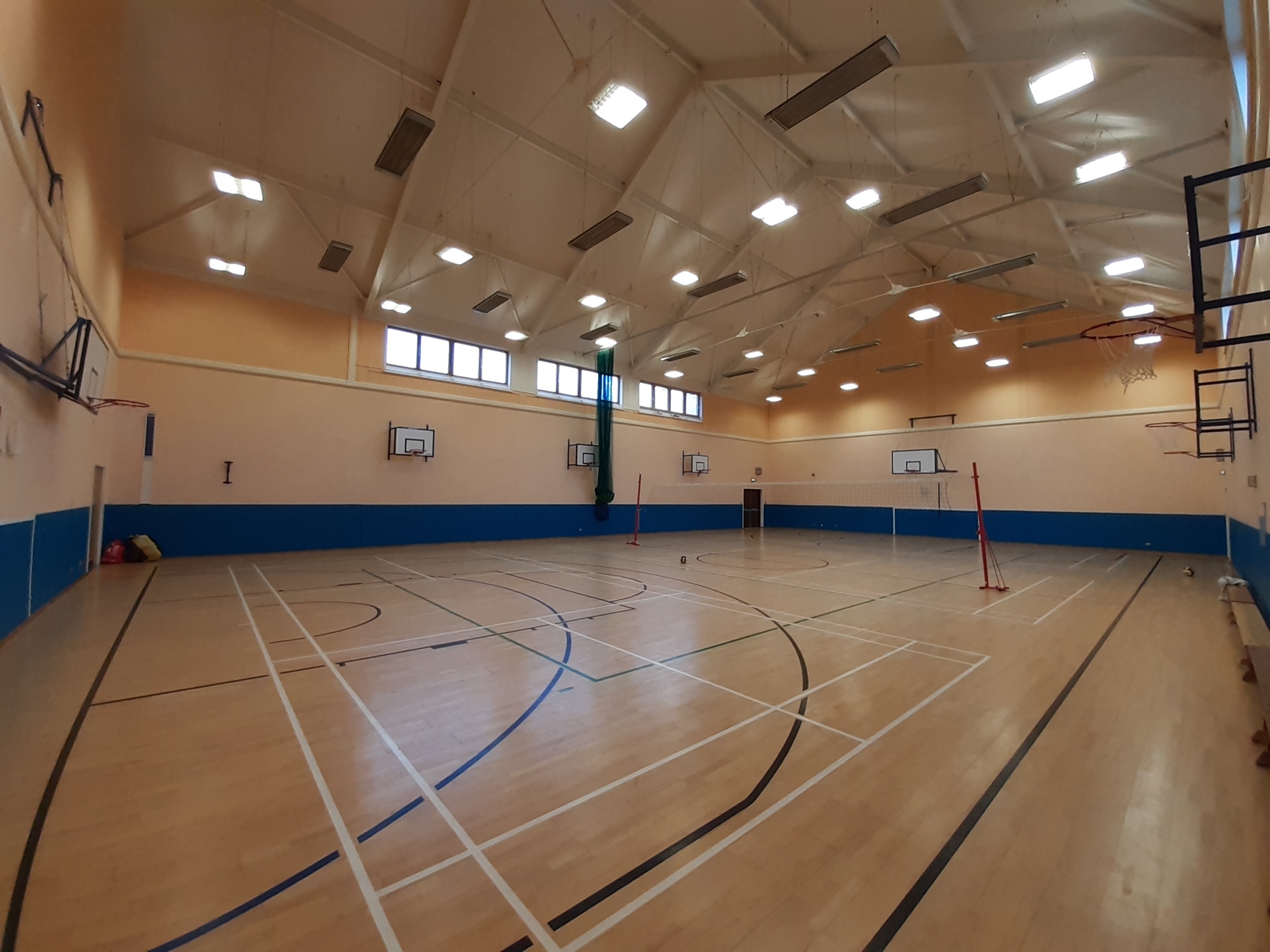 A Games hall featuring floor markings for badminton and basketball, equipped with a net and basketball hoops positioned along each wall.