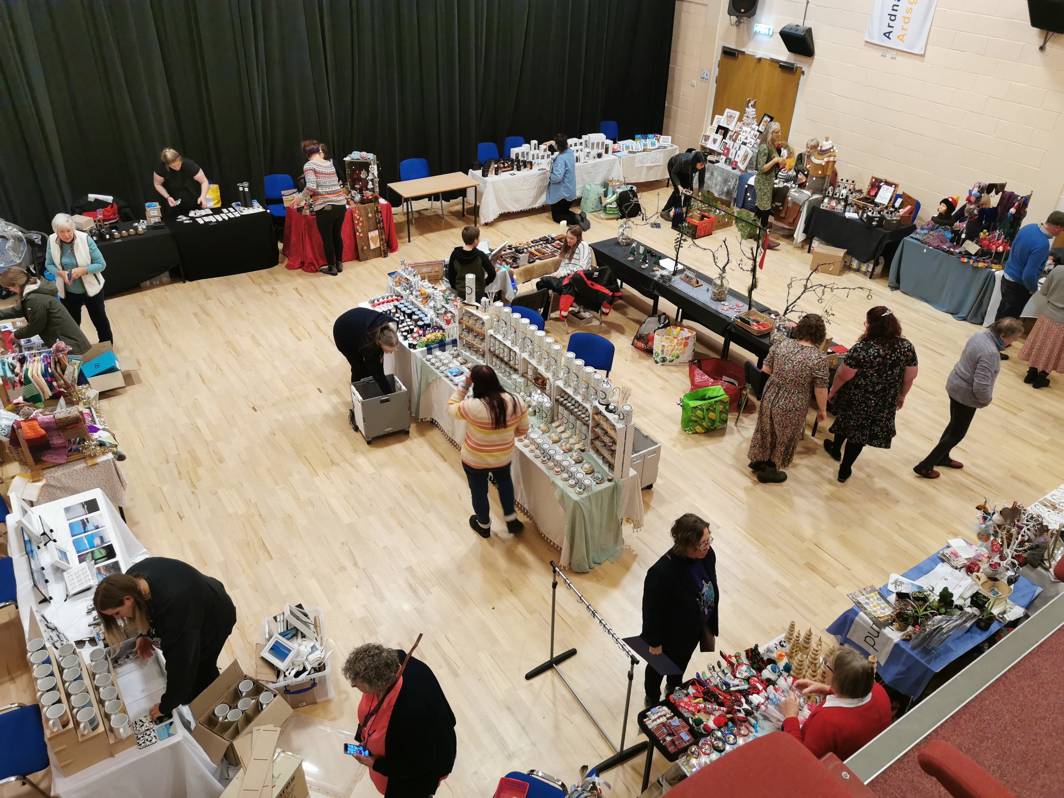 The room is filled with stalls, bustling with shoppers exploring various offerings.