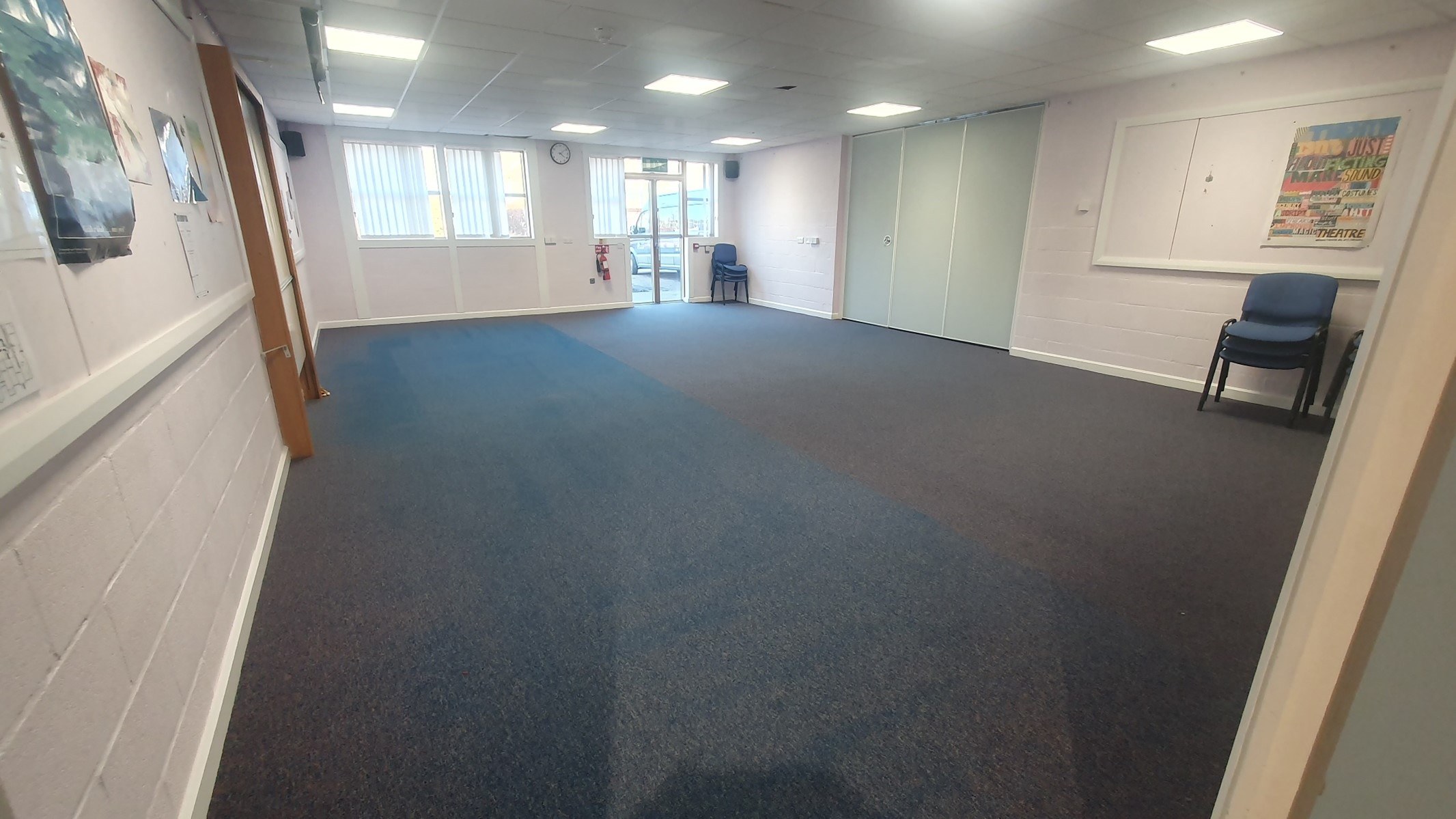 The Assynt room is a generously sized, carpeted space that benefits from ample natural light streaming in through its windows. The walls are adorned with various posters, enhancing the room's overall ambiance. Additionally, a dividing door connects this room to the Lochbroom Room.