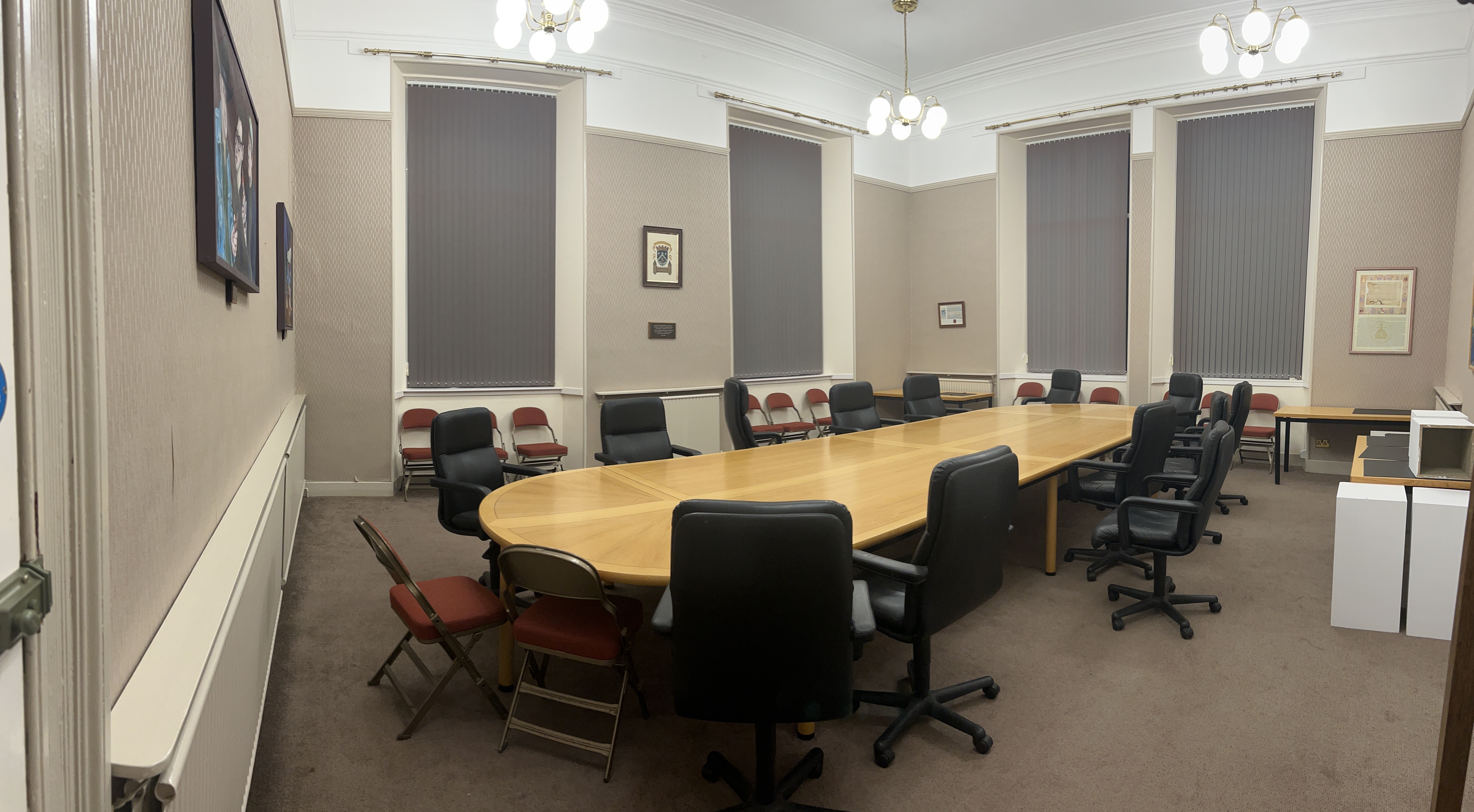 Meeting room equipped with large meeting room table in the centre with accompanying chairs.