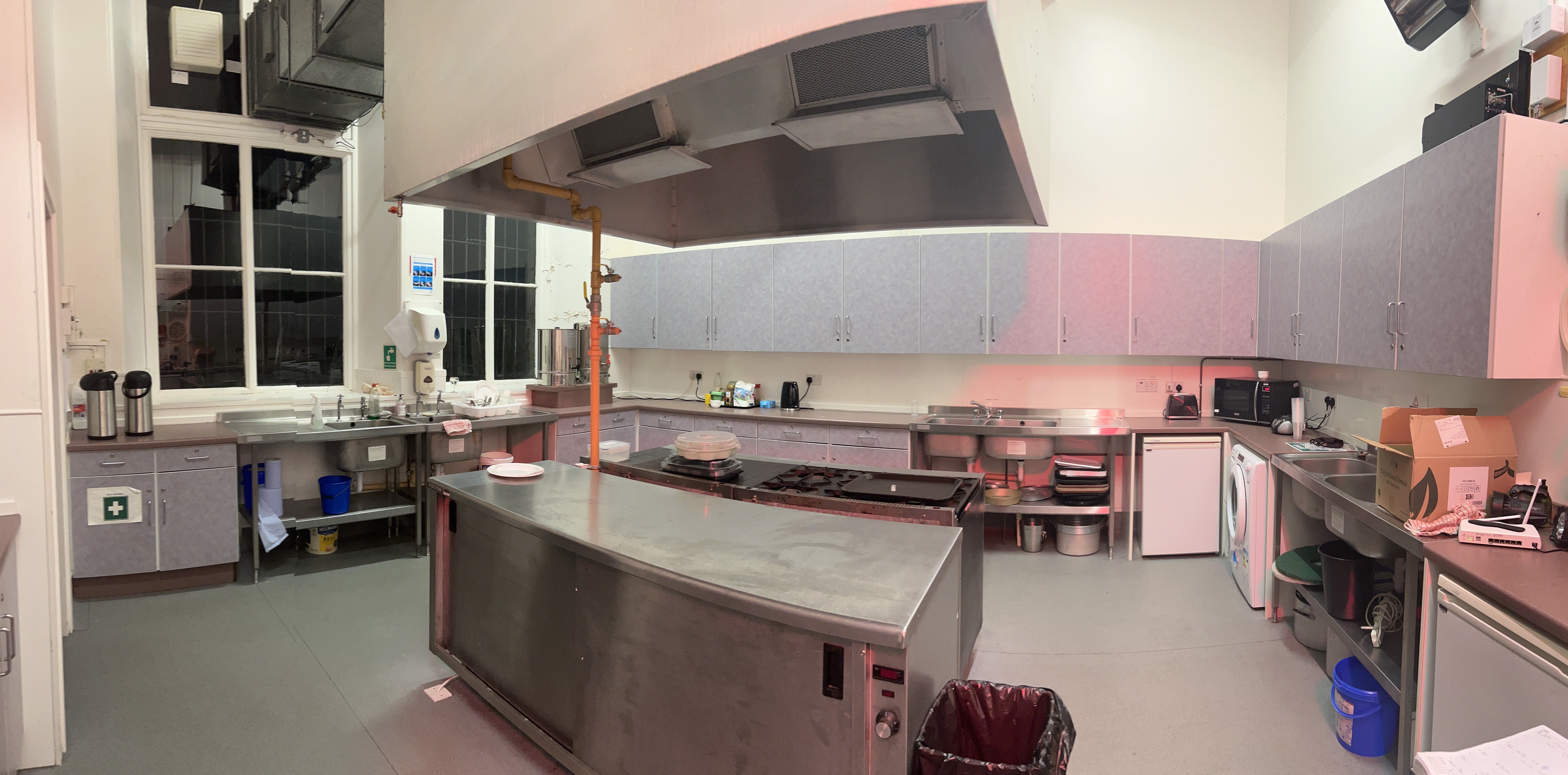 A spacious catering kitchen equipped with an industrial-sized cooker and hob, along with multiple sinks.