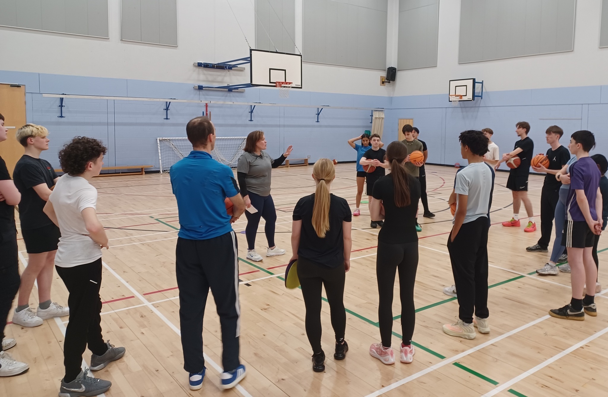 Adults and Young Leaders in a Basketball Leaders course in a gym hall.