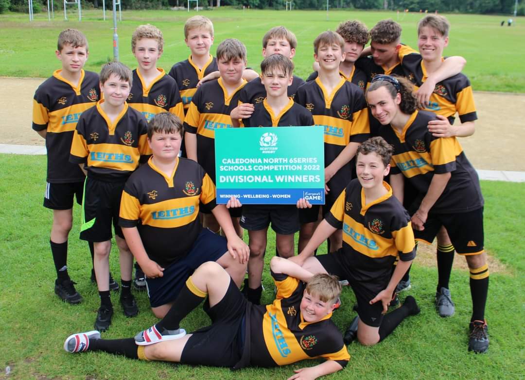 A group of secondary boys in rugby strips holding a cup final title sign.