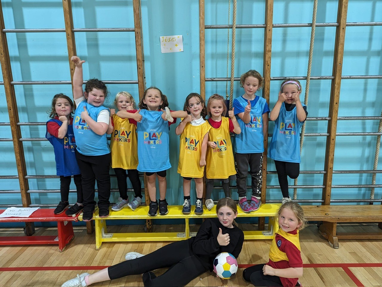 A group of young primary girls looking very happy after a FIFA Disney Playmakers football session.
