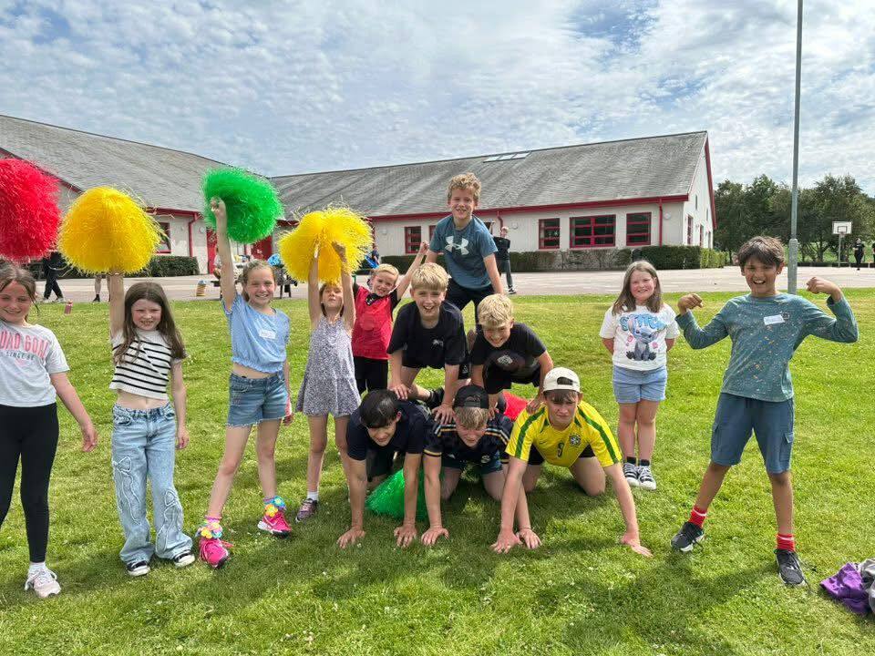 A group of children on Cawdor Primary pitch. Some waving cheer pom poms, and others forming a human pyramid.