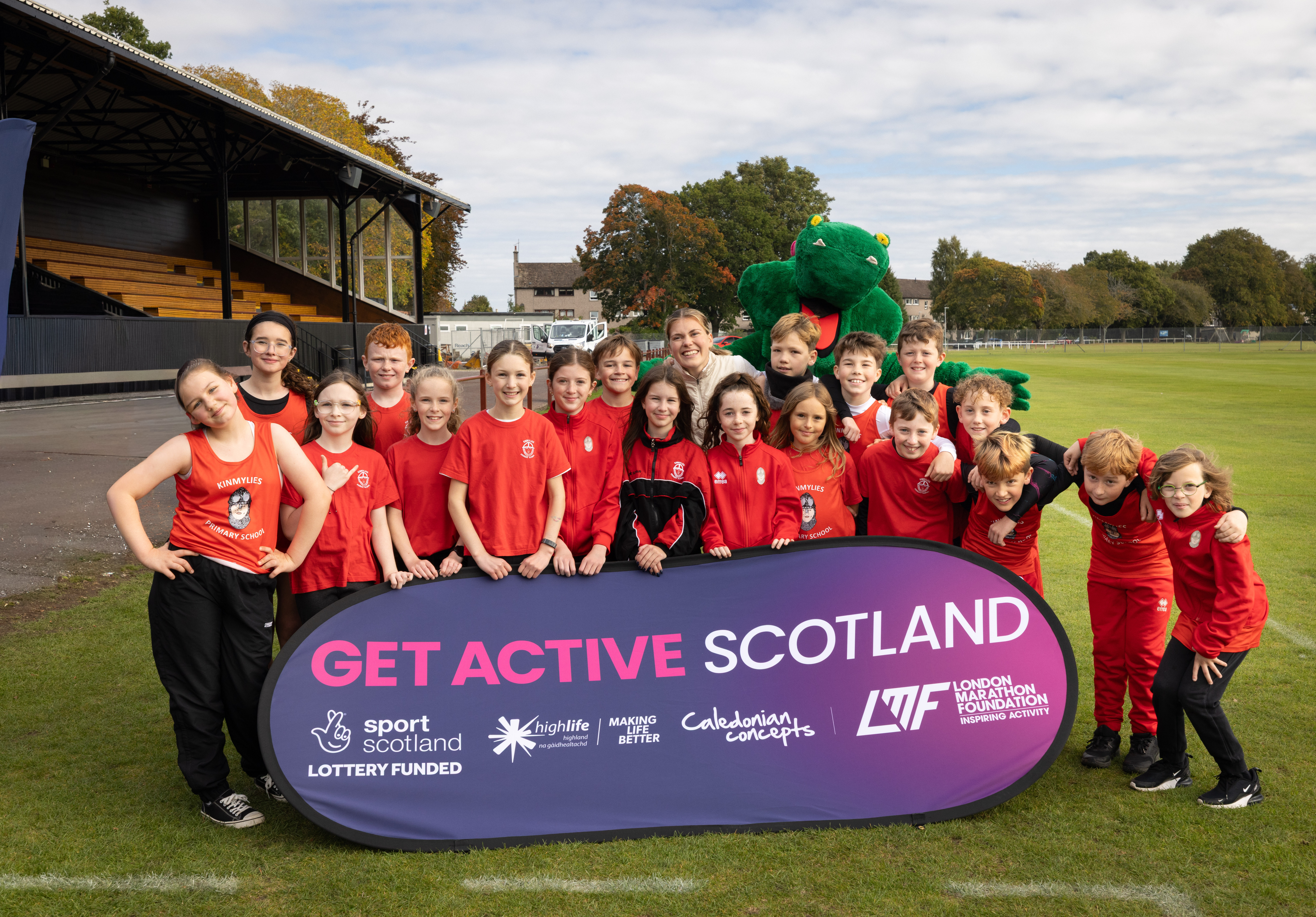 A group of children standing behind a “Get Active Scotland” banner on a sports field.