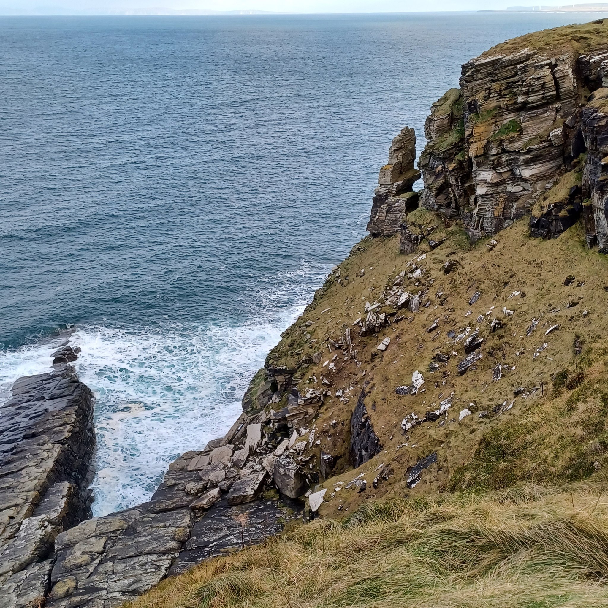 A photo of a sea stack from the top of a cliff edge