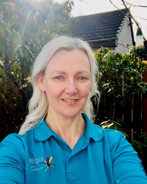 Countryside Ranger in a blue High Life Highland polo shirt outdoors with trees and a house roof visible in the background.