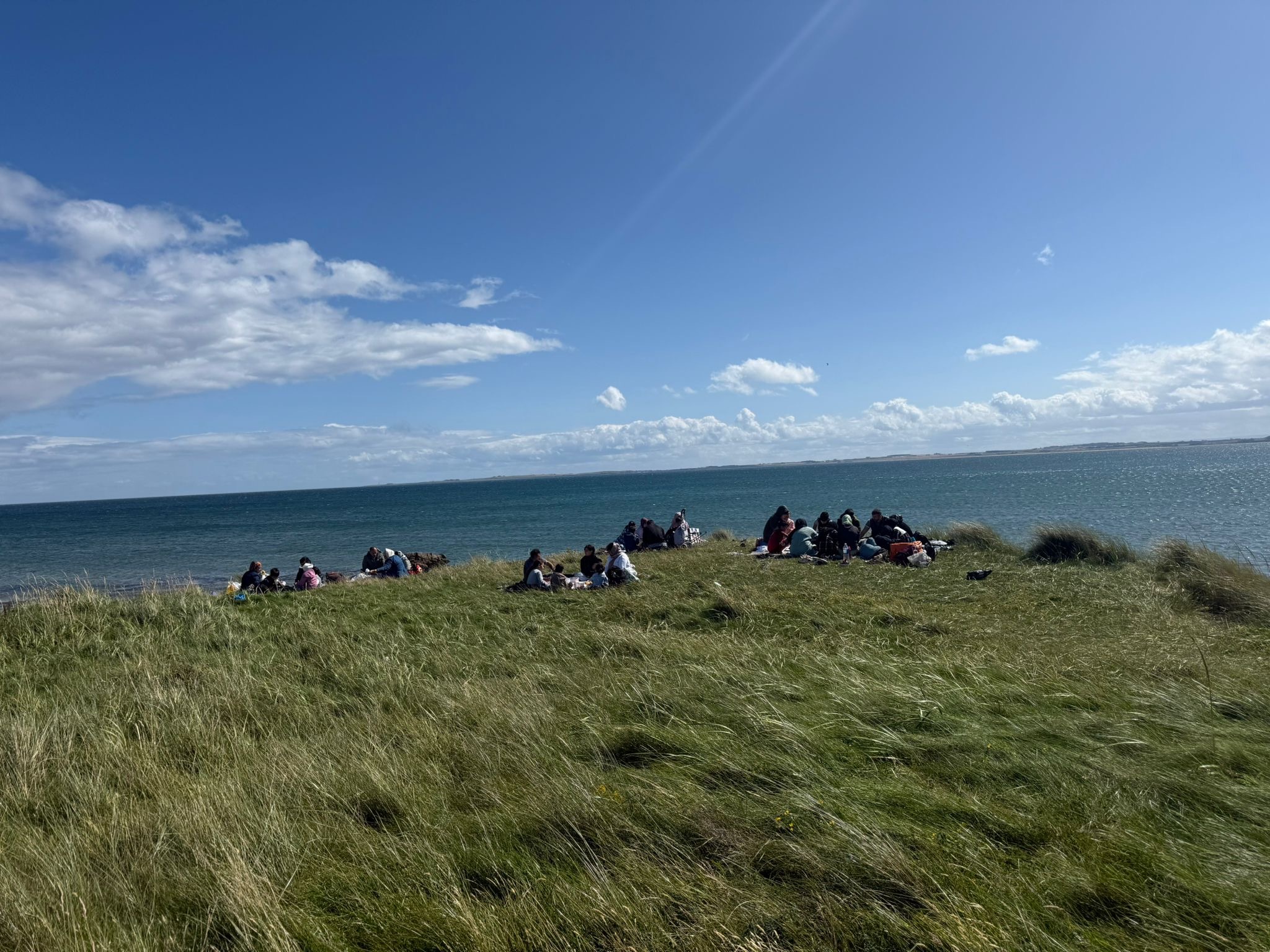 A group sits on the cliff top on a sunny day
