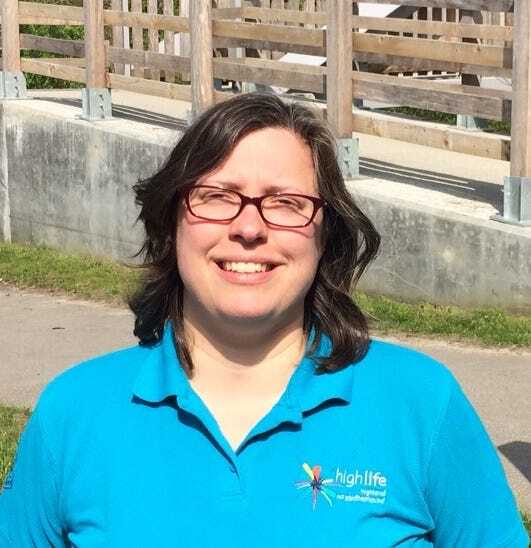 Countryside Ranger in a blue High Life Highland polo shirt standing outdoors near a wooden fence.
