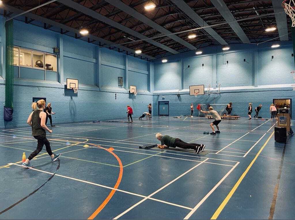 The inside of the Dingwall Leisure gym hall. There are people taking part in a fitness class.