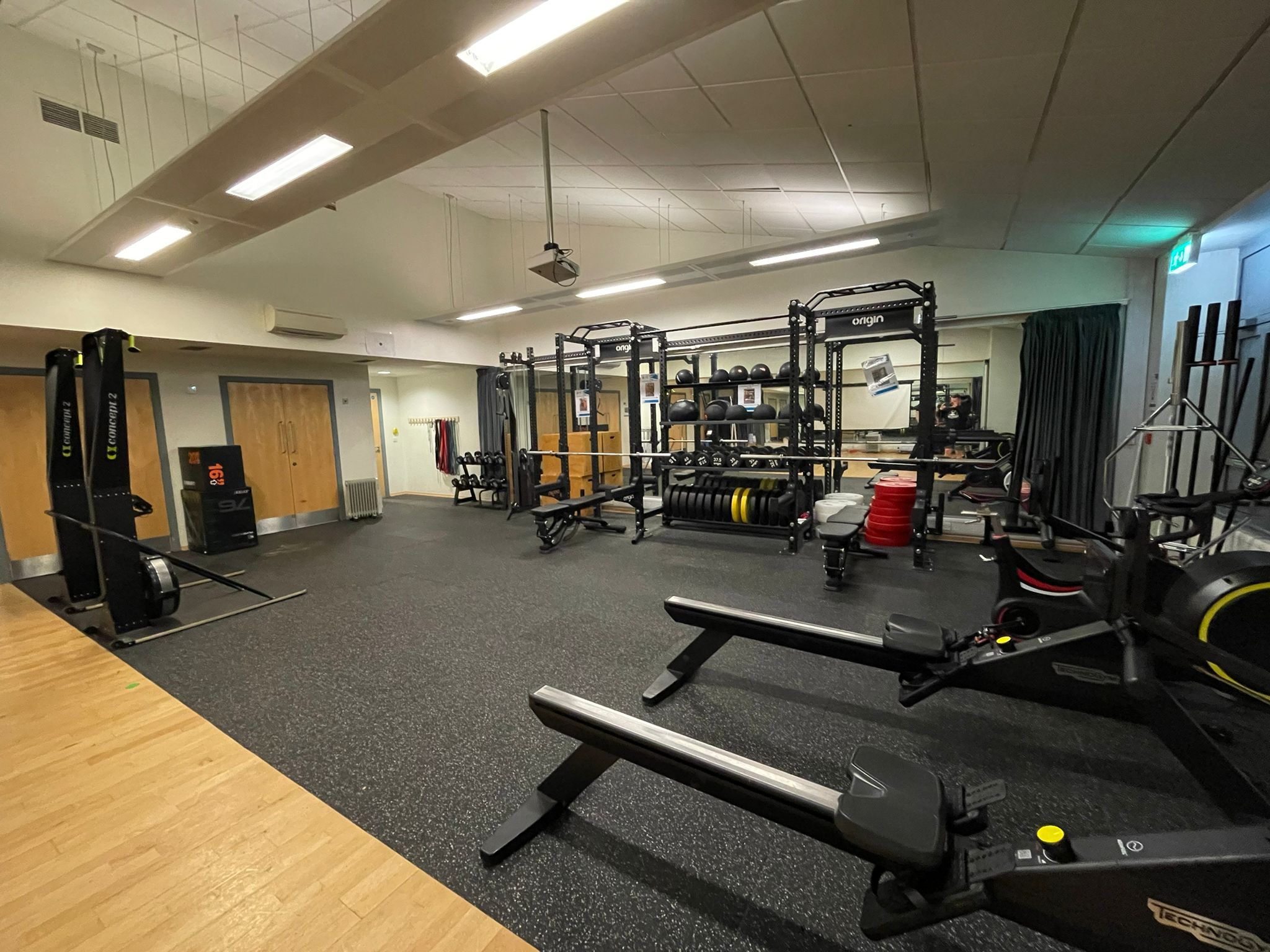 Inside a fitness studio with ski-ergs, rowing machines, weight racks and more.
