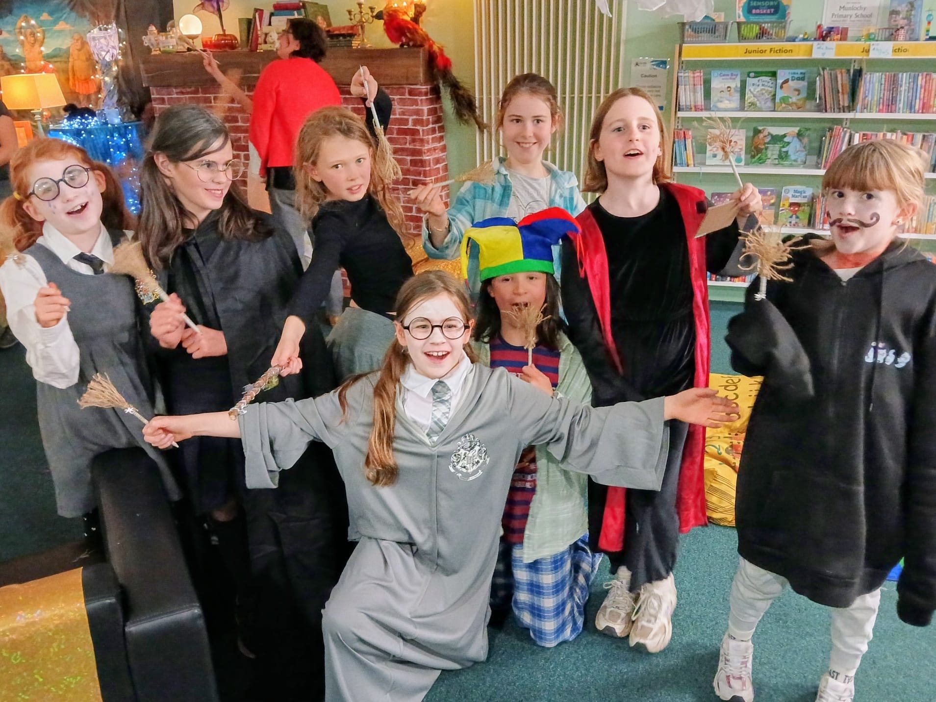 8 children having fun dressing up as witches and wizards inside a library