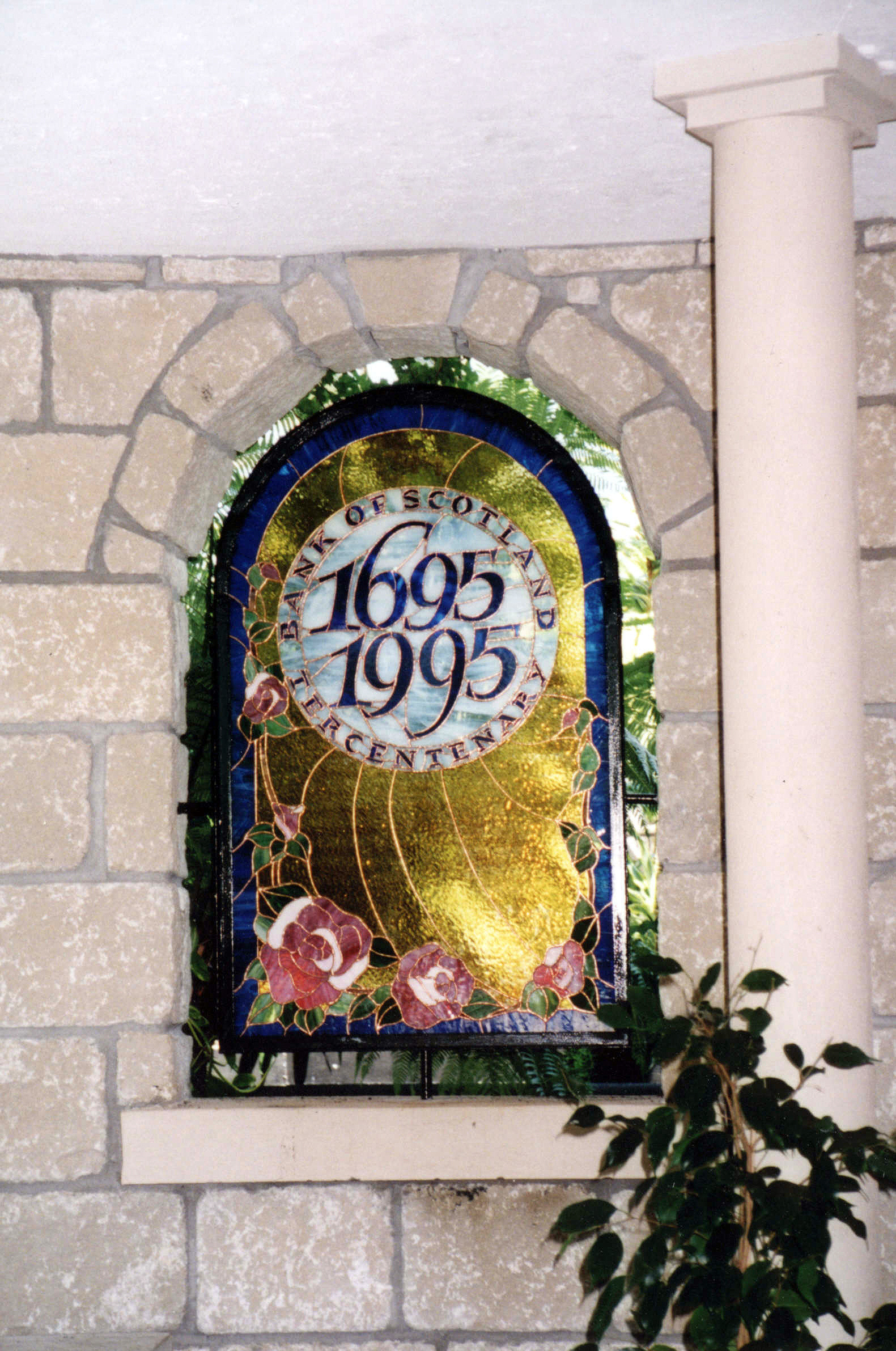 A stained glass window letting colourful light through a walled garden.