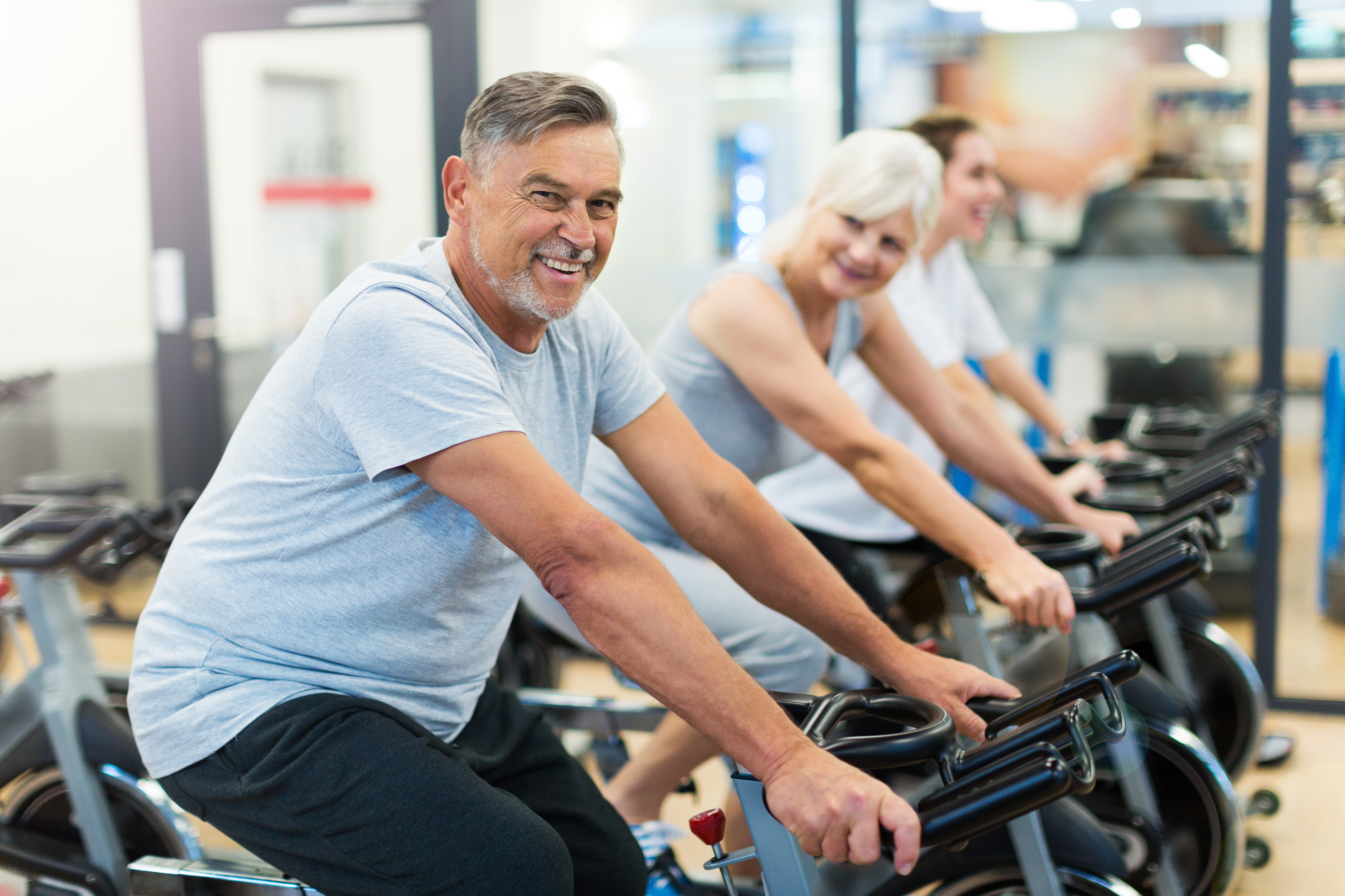 People using stationary exercise bikes in a fitness studio, focusing on indoor cycling for health and fitness.
