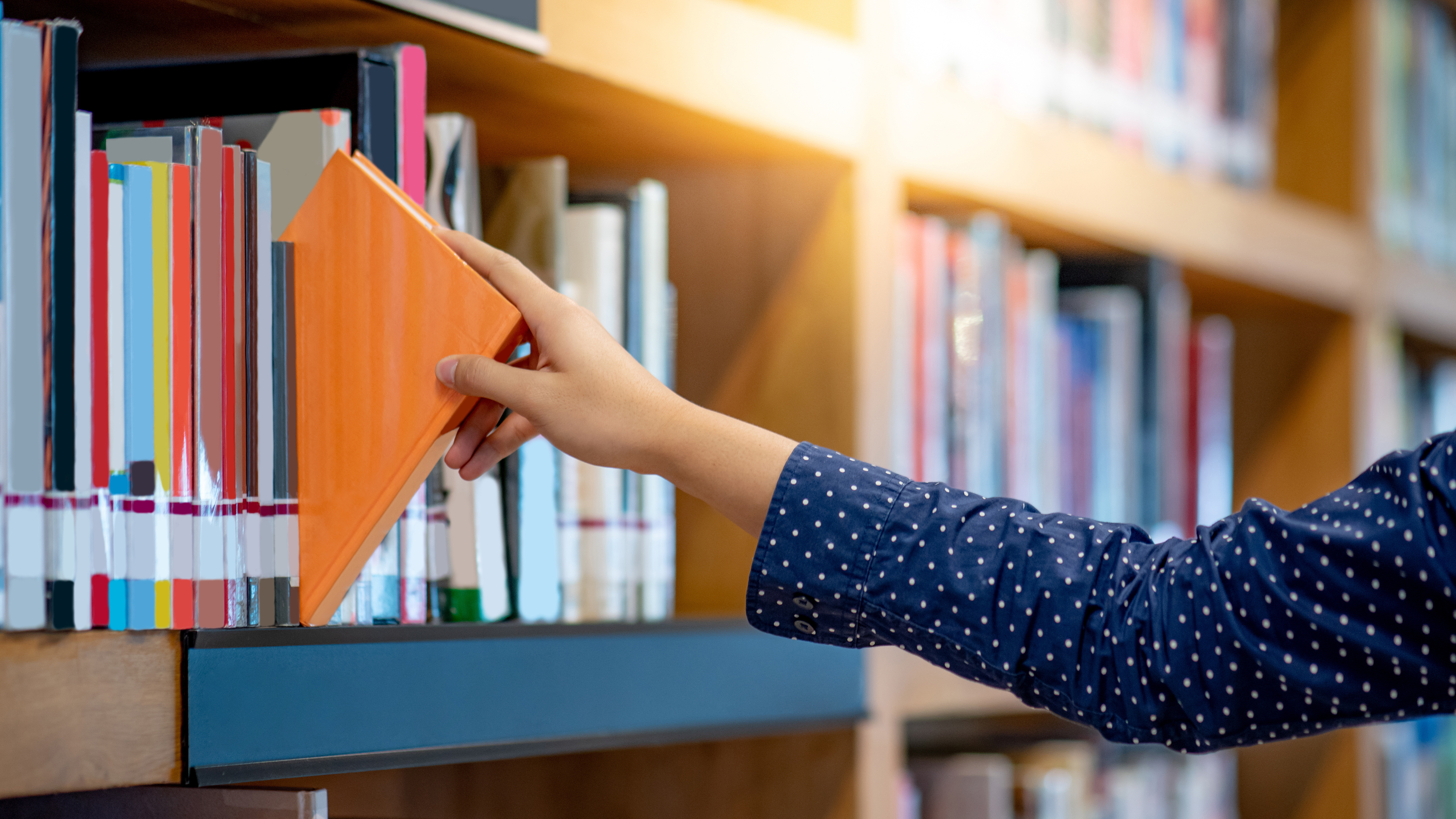 A person selecting a book from a shelf