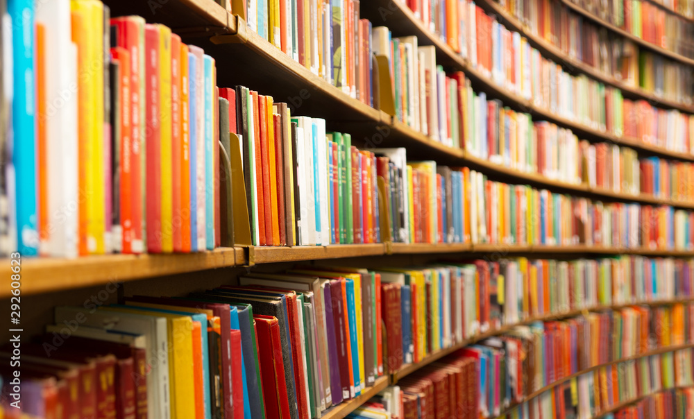 Rows of colorful books on curved wooden shelves in a library.