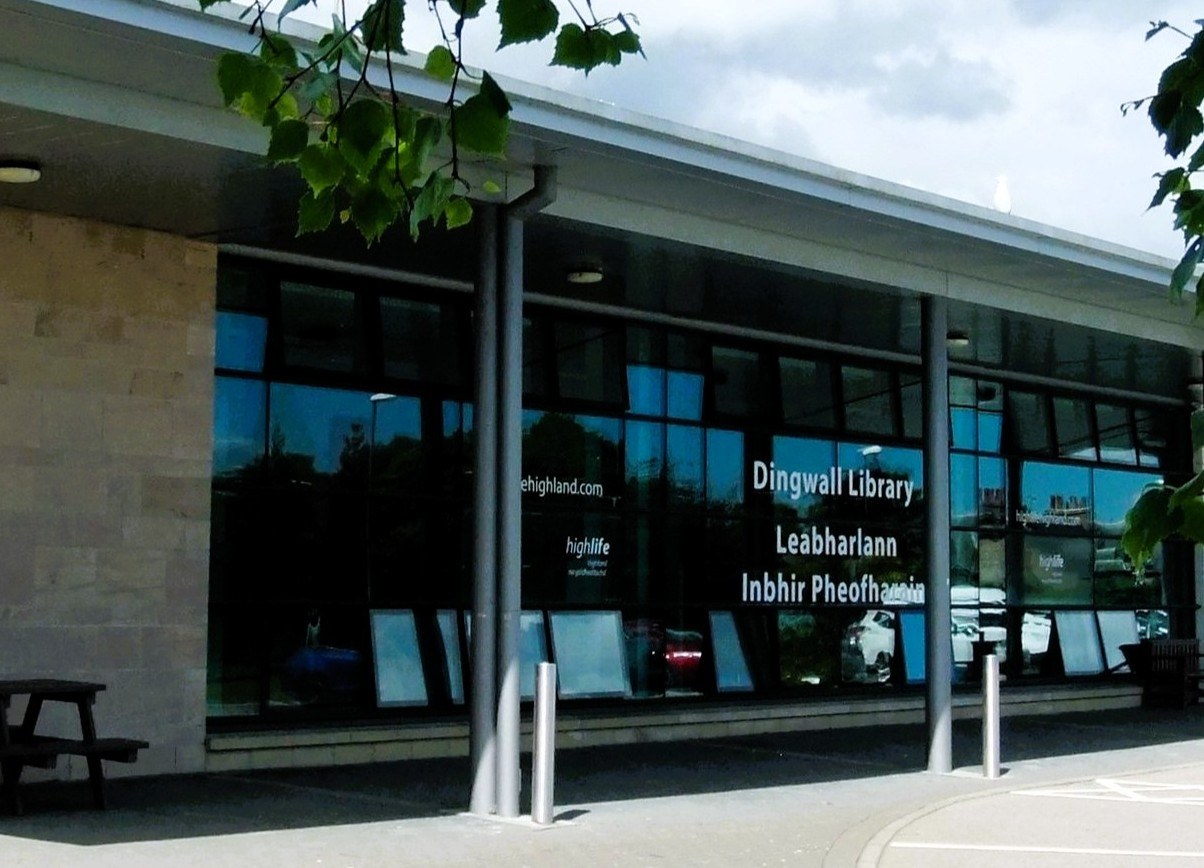 Exterior of Dingwall Library, modern building with large glass windows and bilingual signage on the front.