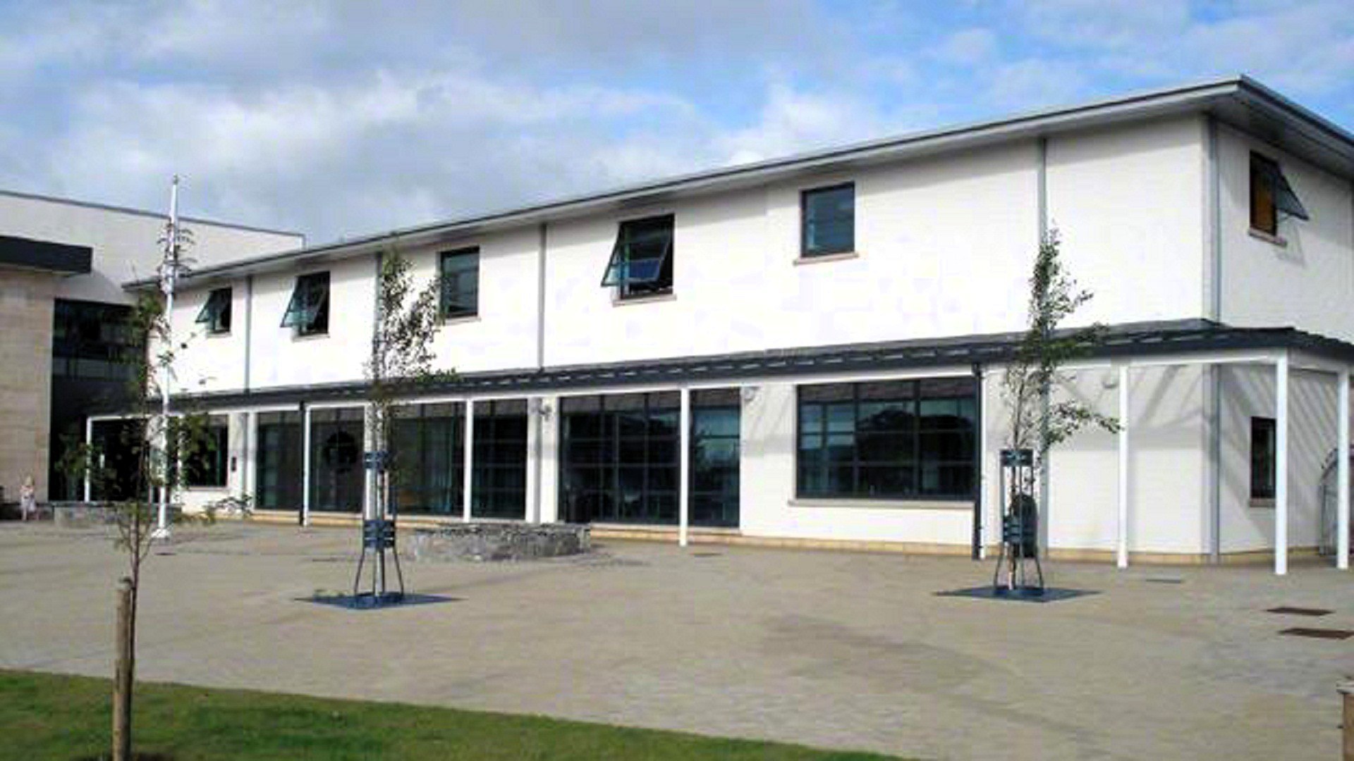 Exterior of Portree Library, modern two-storey white building with large windows and covered walkway in front.