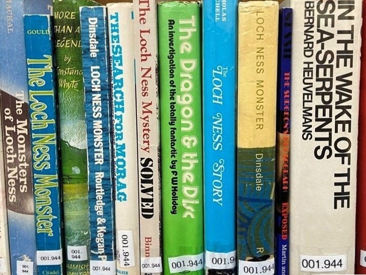 Books on a library shelf about the Loch Ness Monster and sea creatures, with various colourful spines and titles visible.