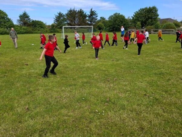 Young kids running around football pitch.