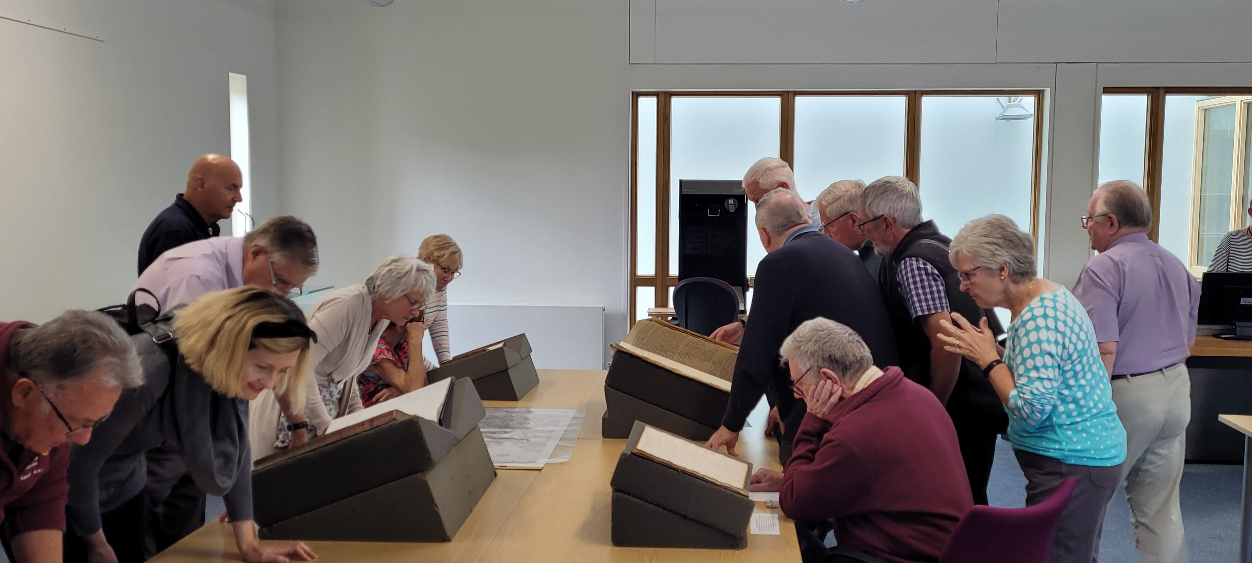 A group of people in a light bright room looking at a display of archive documents