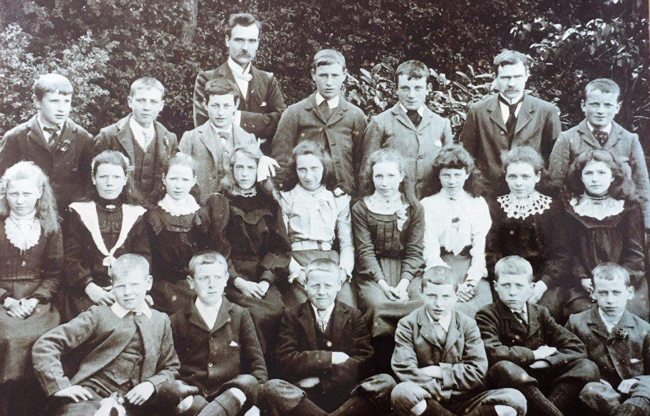 A black and white formal photograph of pupils and teachers in Edwardian clothing