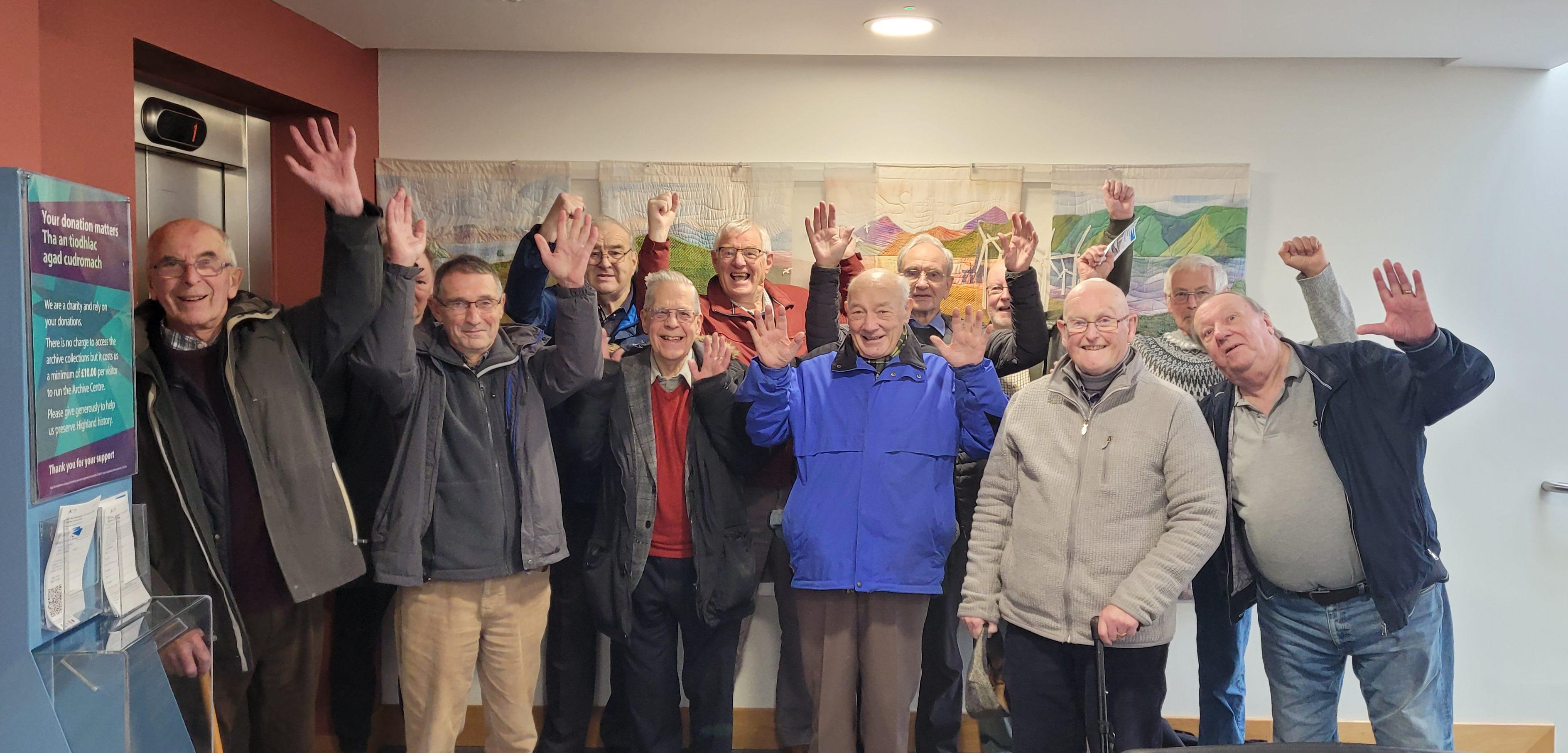 A group of men waving and cheering inside a building
